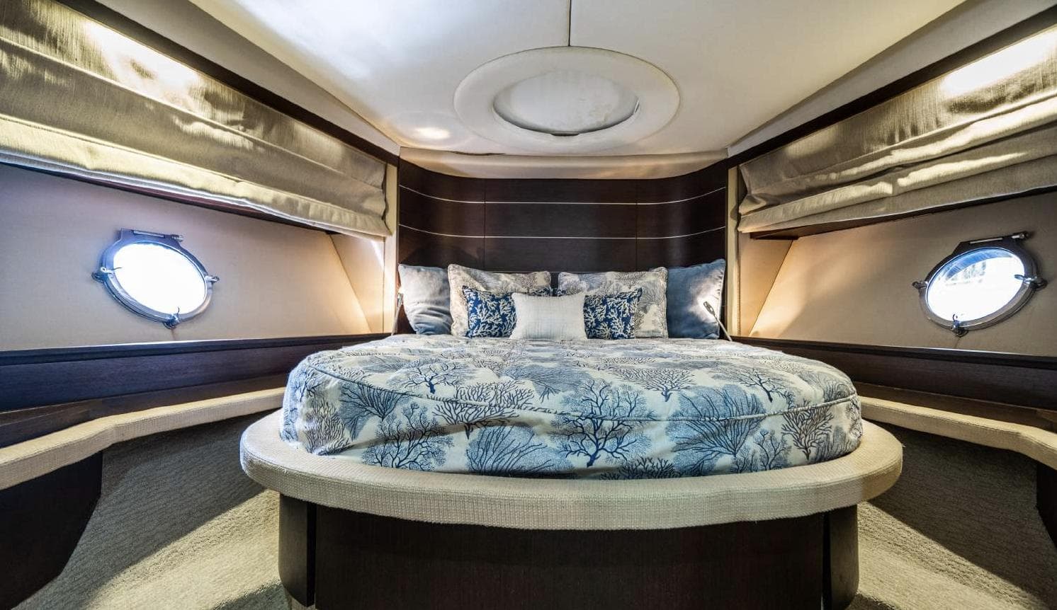 Luxurious bedroom interior of 2005 Azimut 68S yacht with elegant bedding and porthole windows.