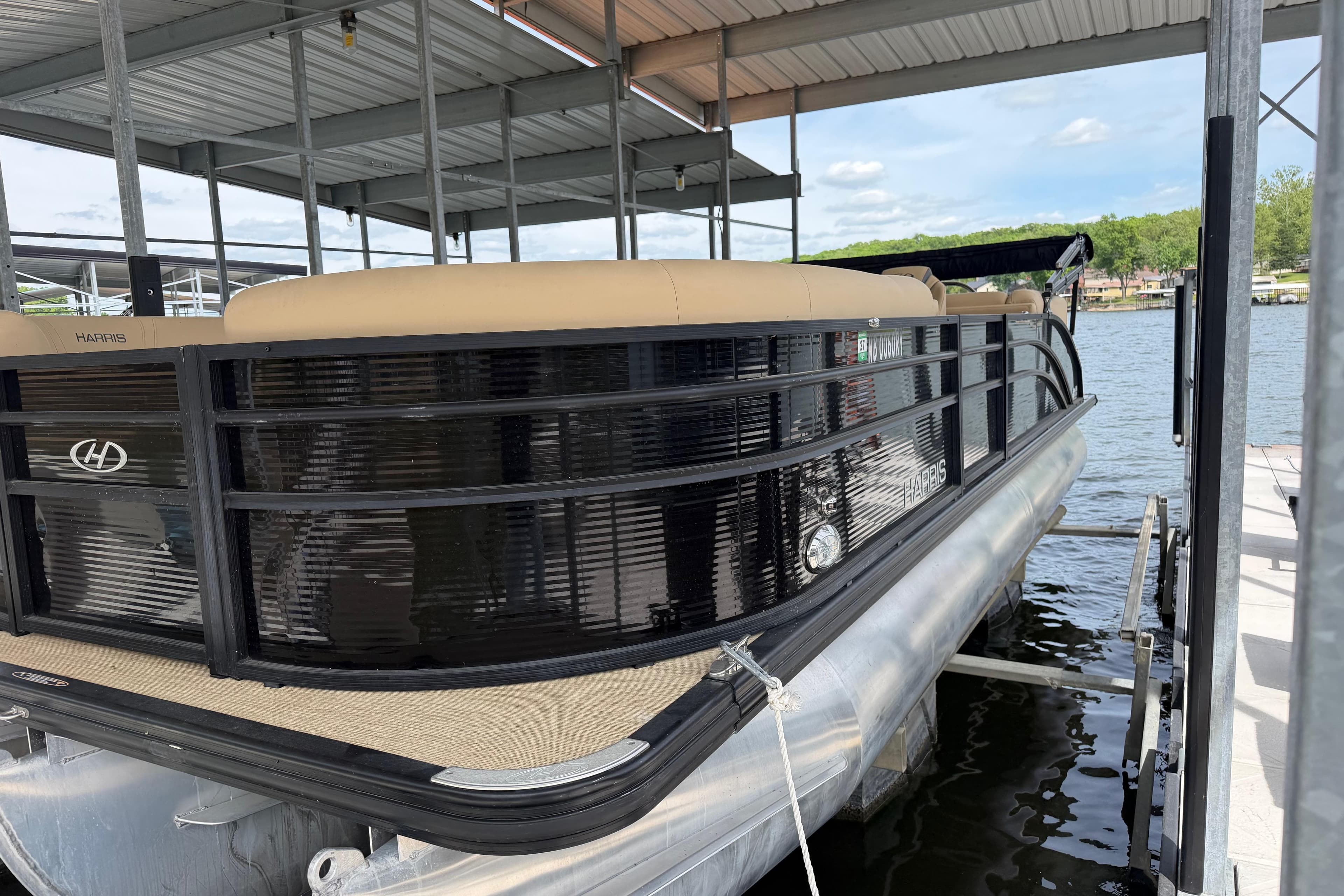 2023 Harris Cruiser 250 CW pontoon boat docked under a covered marina.