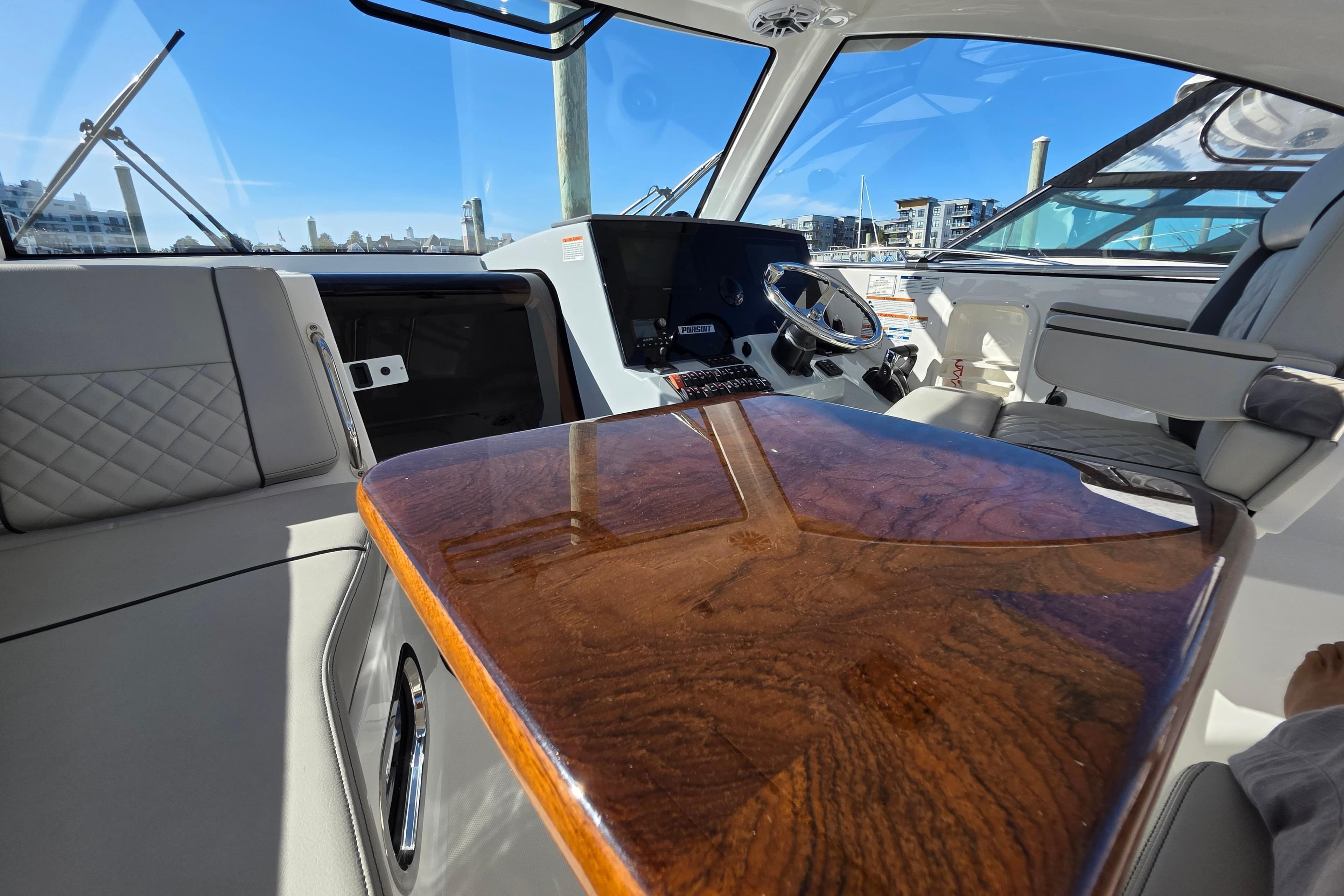 2024 Pursuit OS 325 Offshore boat interior with polished wood table and modern helm.
