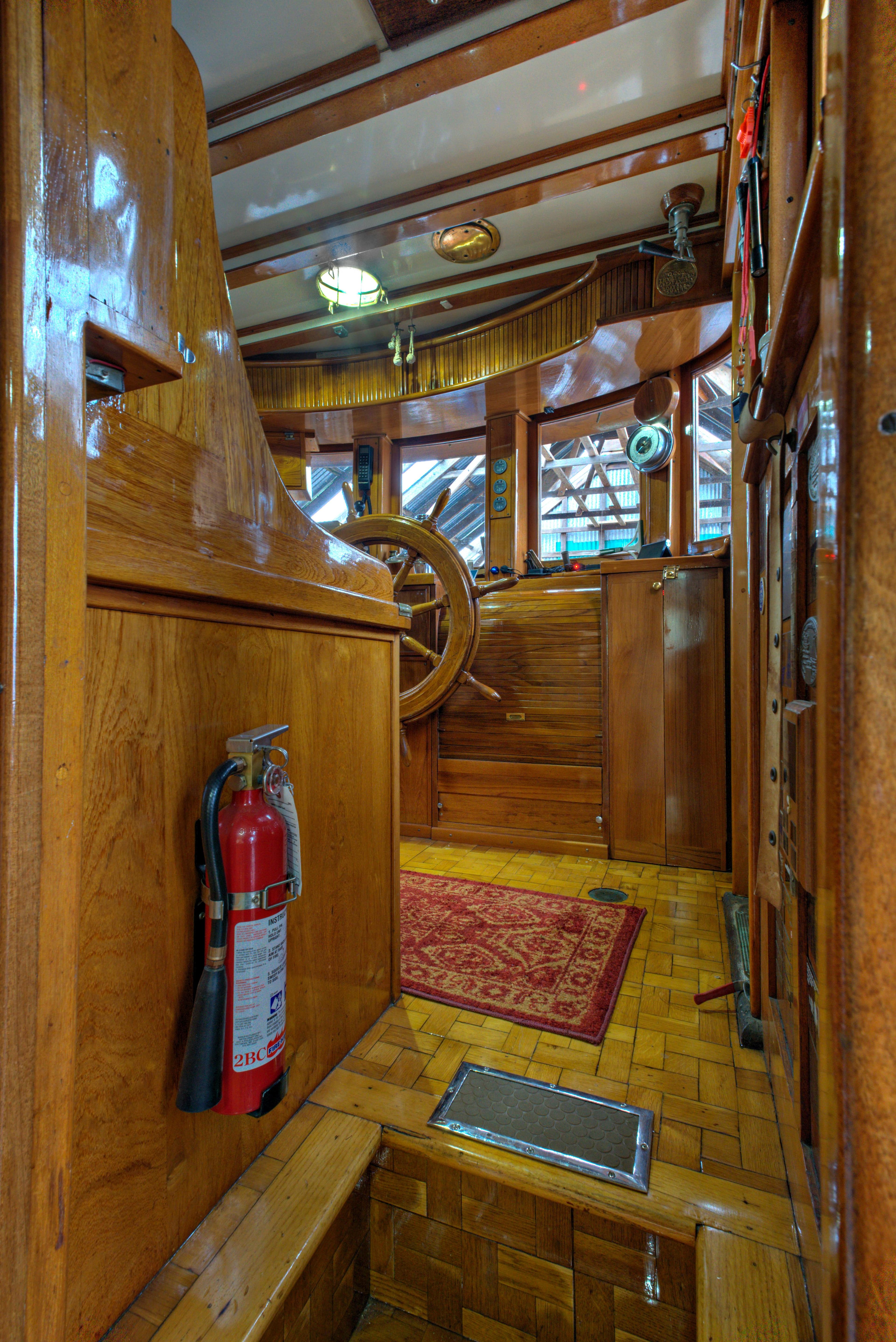 1929 Custom HOFFAR-BEECHING Fantail Yacht interior with wooden helm and fire extinguisher.