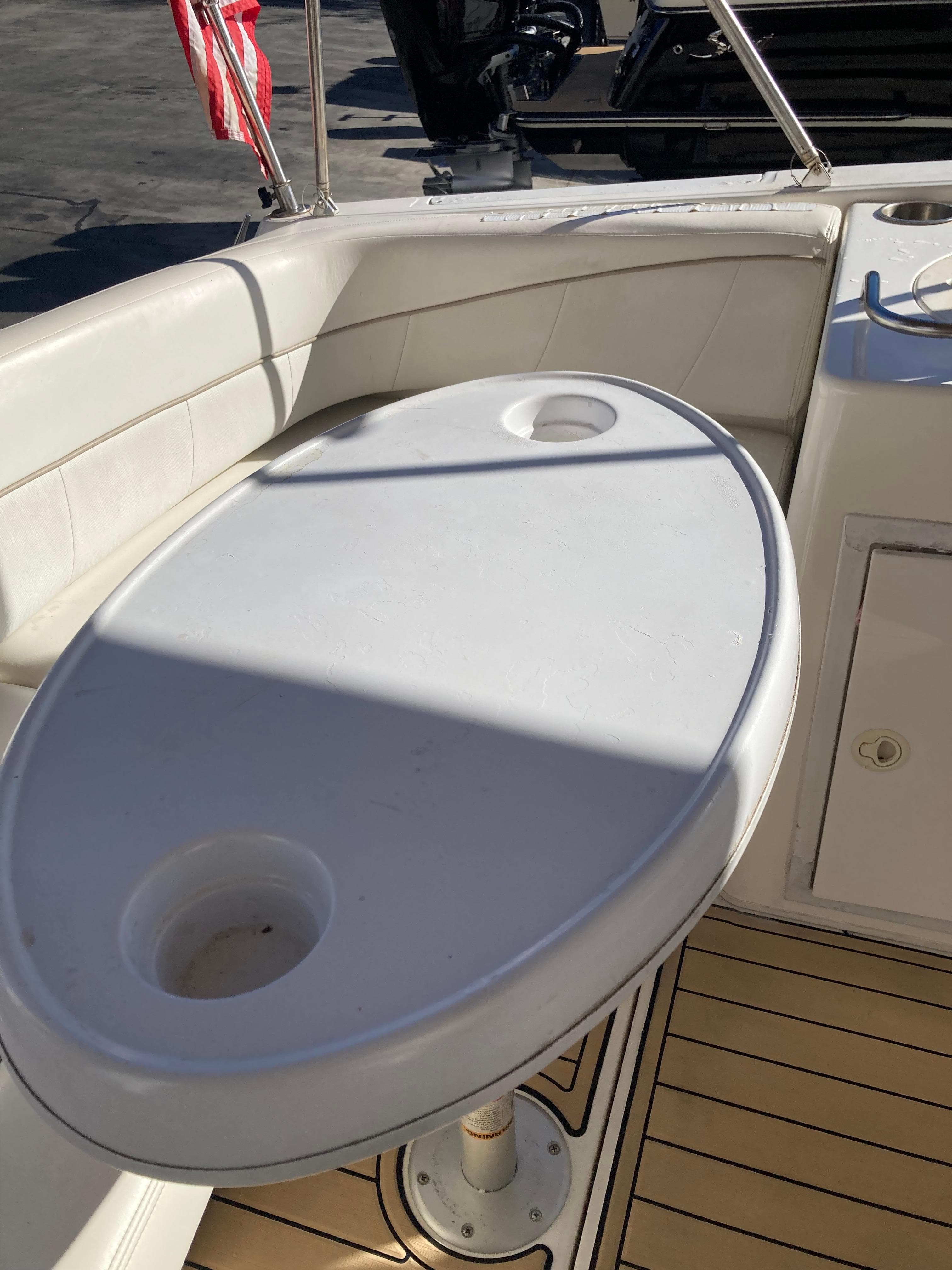 Oval table on 2000 Larson Cabrio 290 boat deck with cup holders.