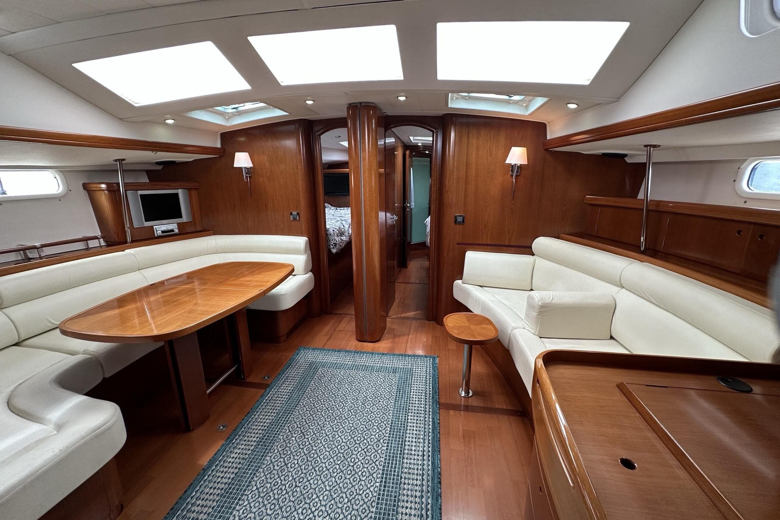 Luxurious interior of a 2003 Beneteau 57 yacht with elegant wood finishes and plush seating.