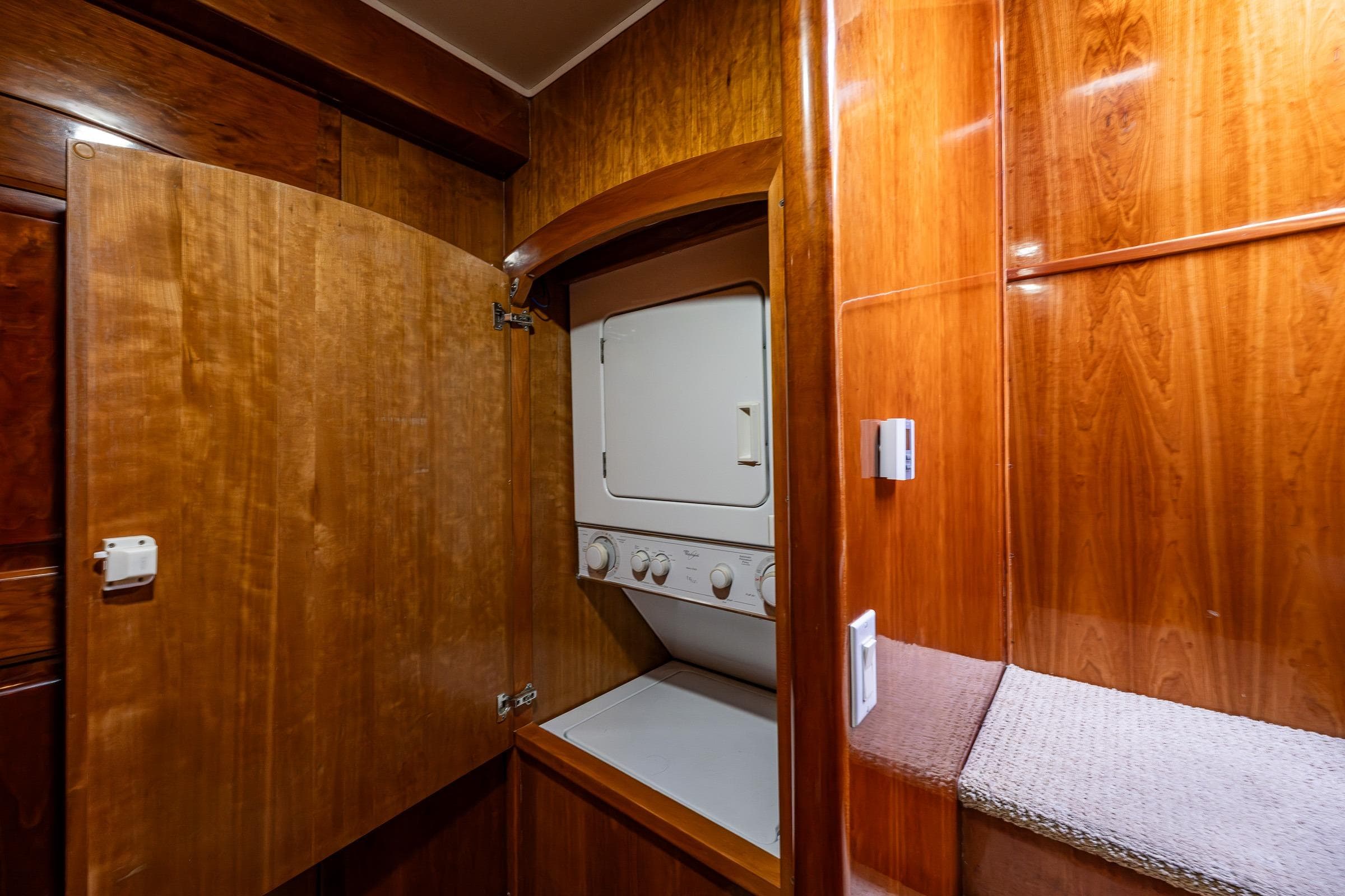 Laundry area in 2001 Navigator Pilothouse with wooden cabinetry and stacked washer-dryer.