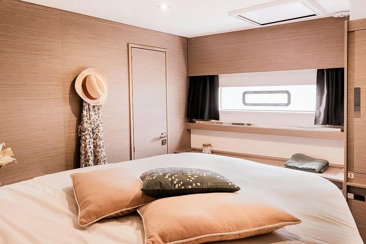 Luxurious cabin interior of 2026 Fountaine Pajot Aura 51 yacht, featuring elegant decor and cozy bedding.