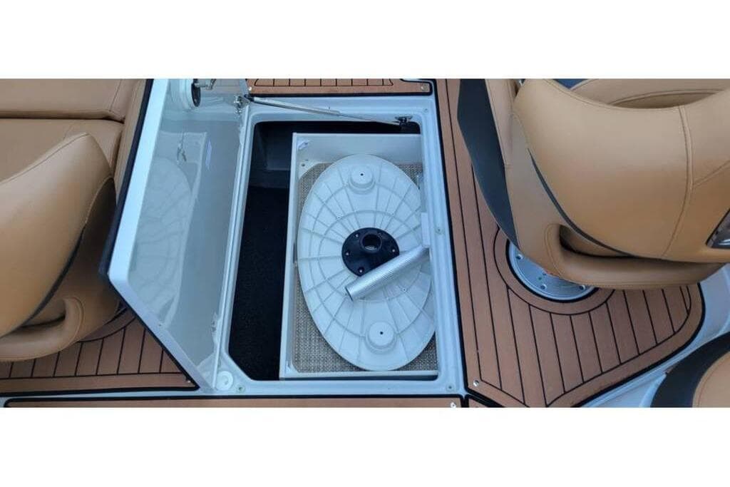 2024 Crownline Eclipse E235 boat storage compartment with teak flooring and tan seating.