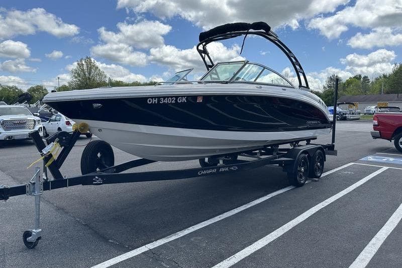 2023 Chaparral 23 Surf boat on trailer in parking lot under cloudy sky.