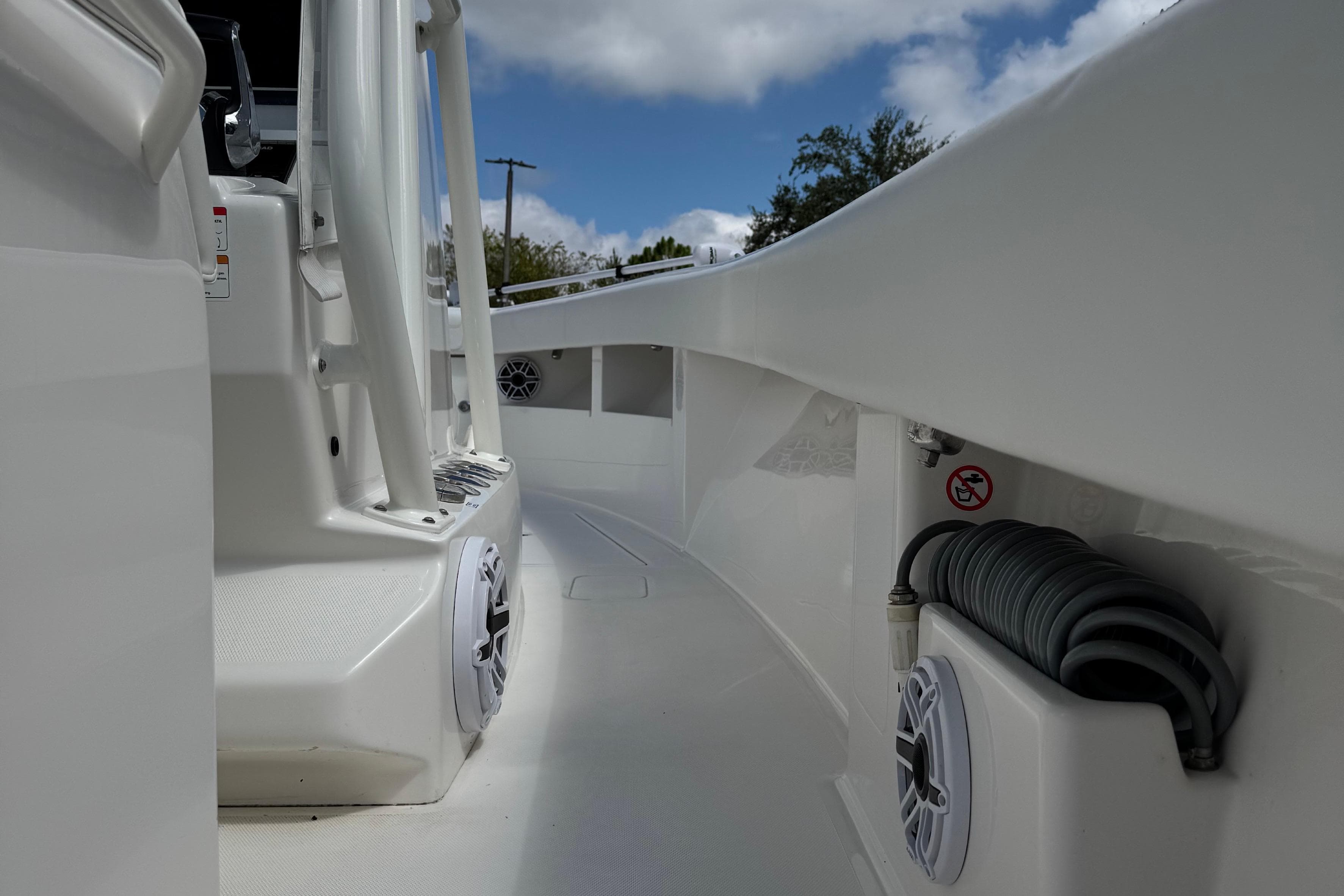 2024 SeaVee 32Z boat deck with speakers and coiled hose, under a partly cloudy sky.