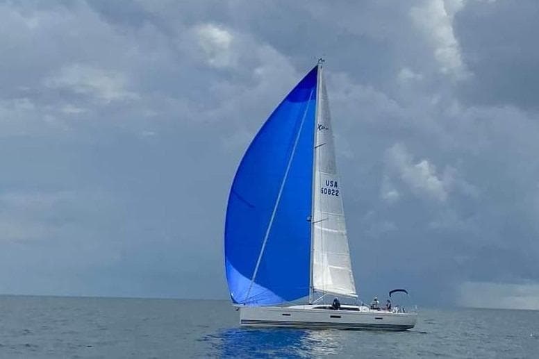 2016 X-Yachts XP-44 sailing with blue spinnaker under cloudy skies.