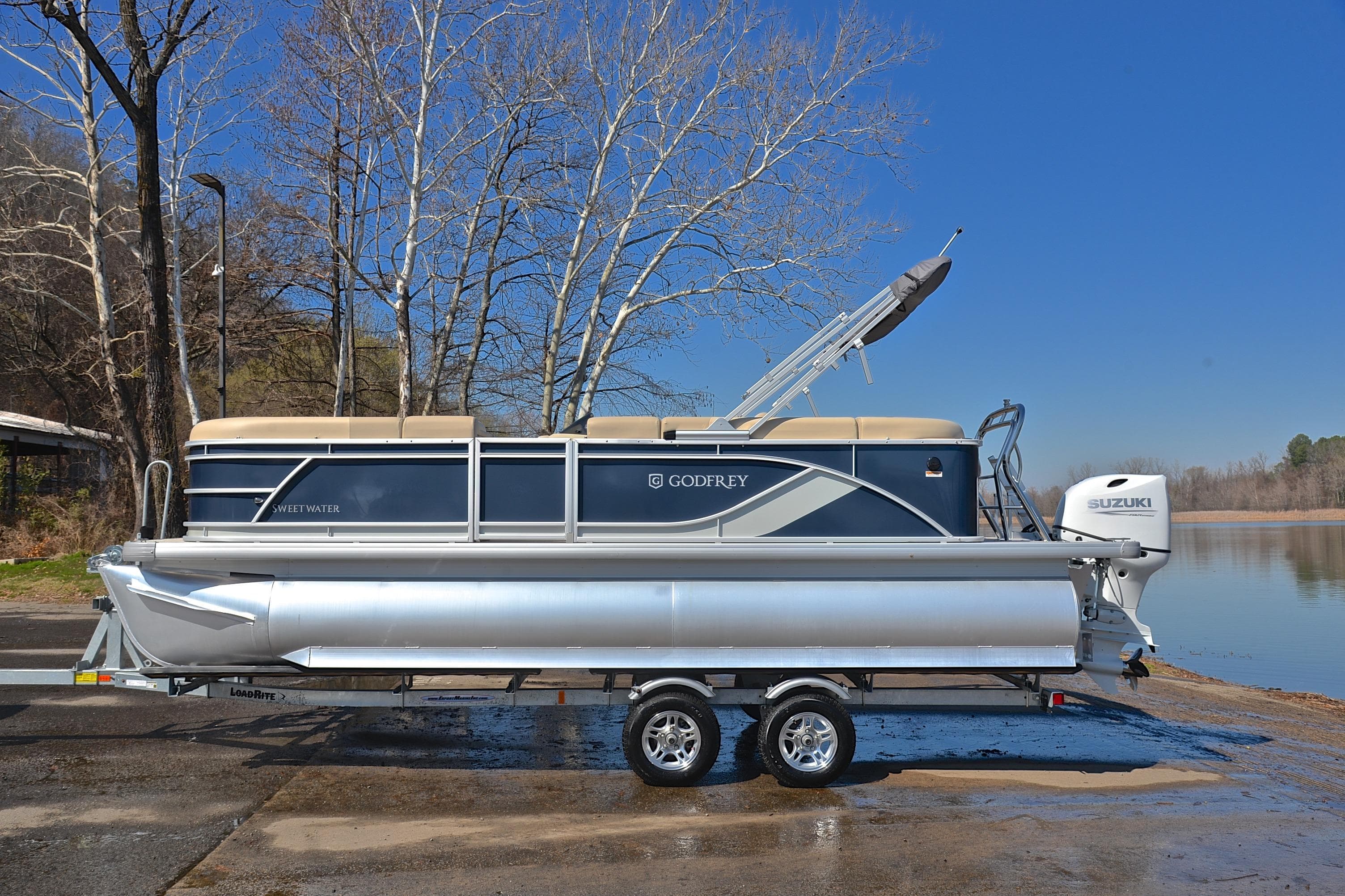 2025 Godfrey Sweetwater 2086 C pontoon boat on trailer by a lake.