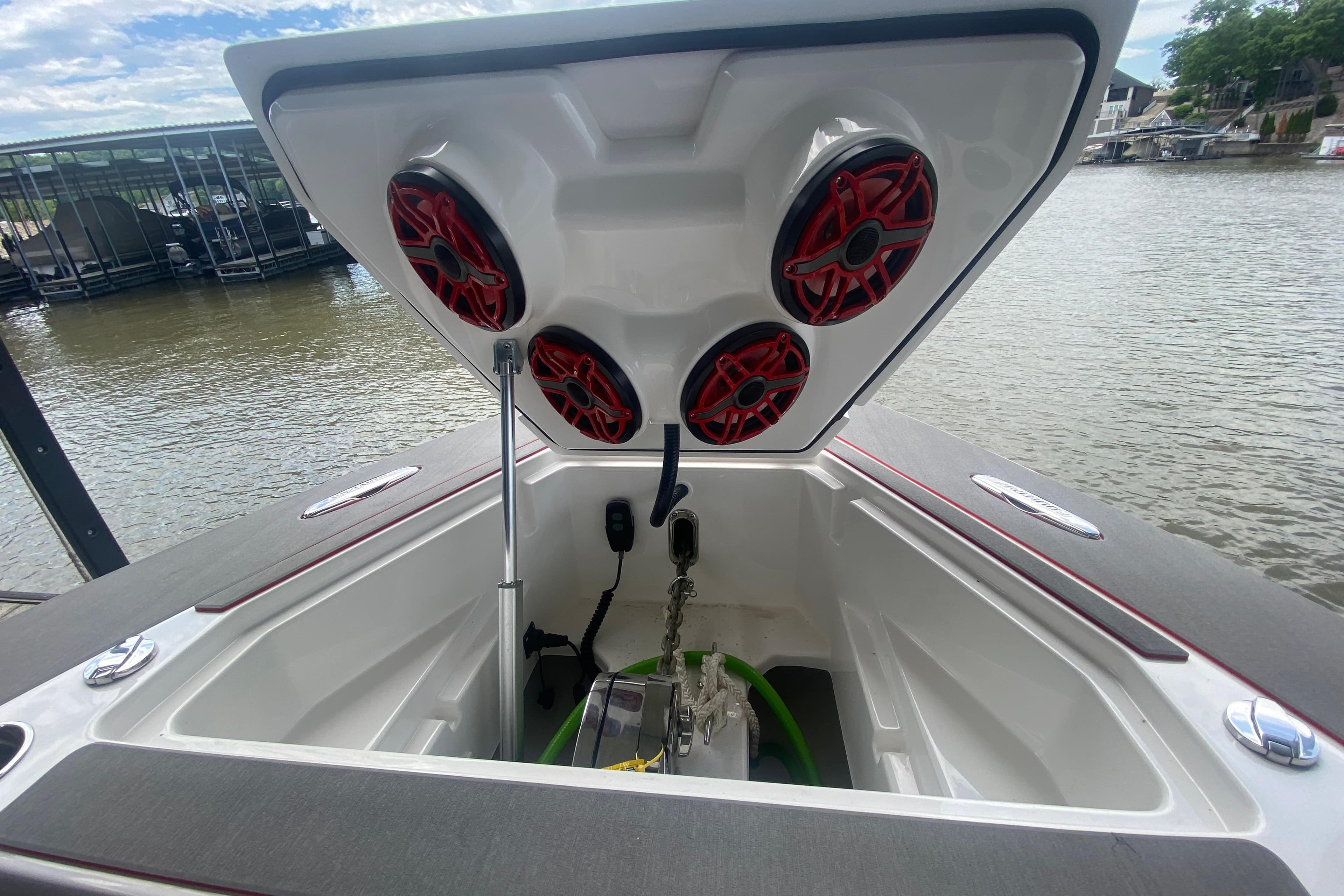 2025 Fountain 38 SCX boat storage compartment with red speakers, docked by the water.