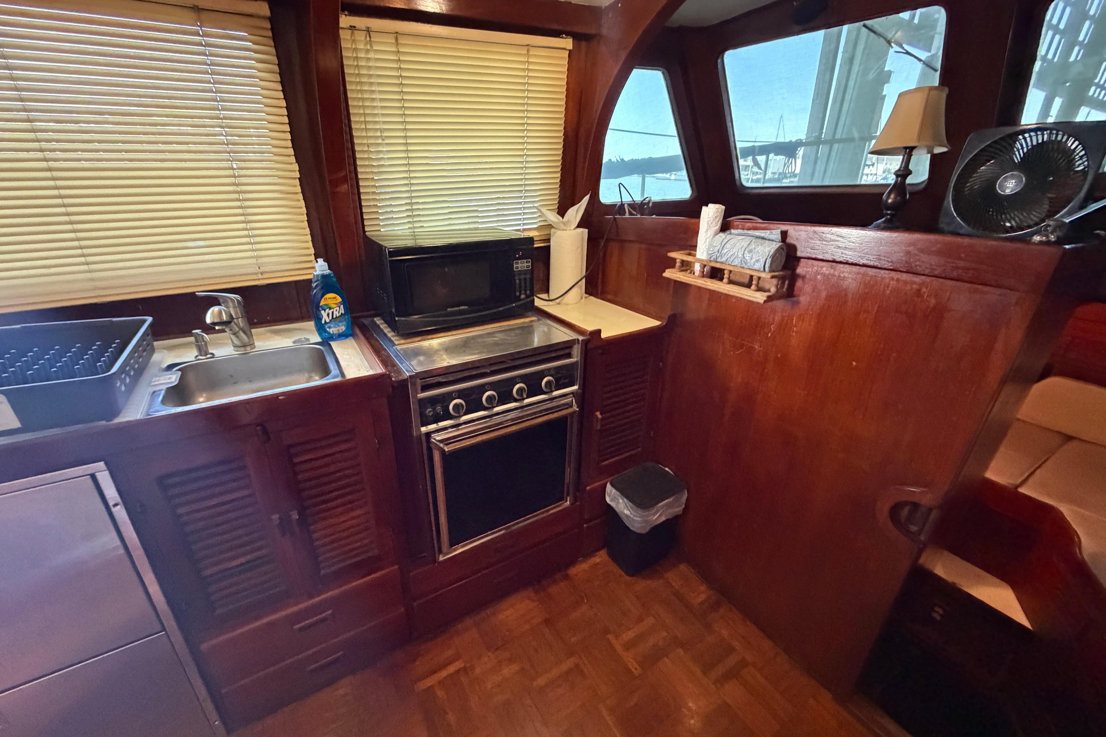 1978 Albin 36 Trawler kitchen with wooden cabinetry, stove, and microwave.