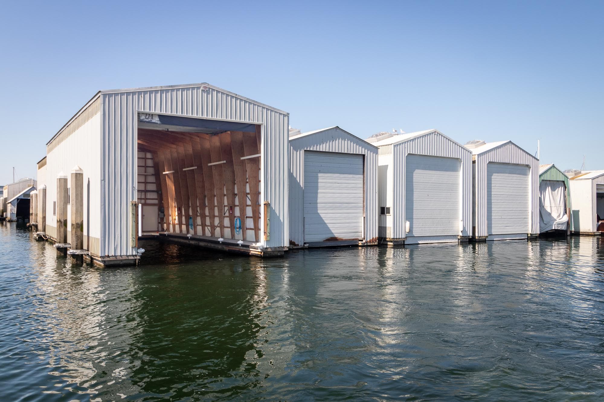 Boat storage sheds on water, featuring Tiara Yachts C44 Coupe, 2023 model.