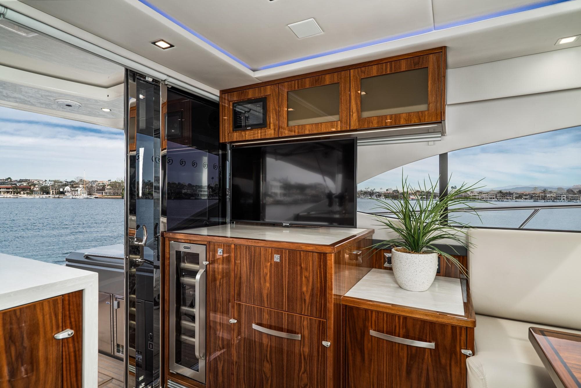 Luxurious interior of 2020 Riviera 5400 Sport Yacht with elegant wood cabinetry and scenic ocean view.