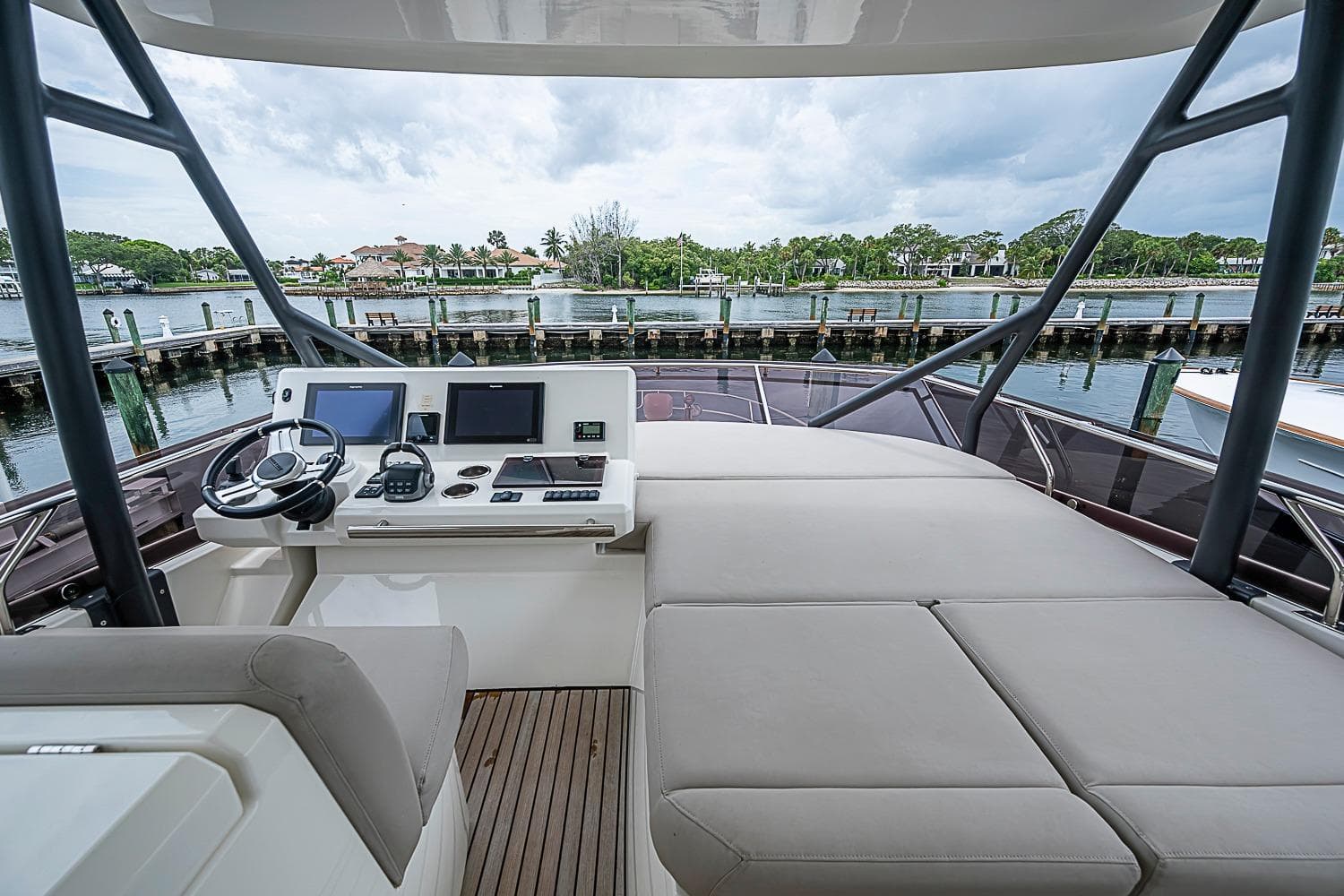 Flybridge of 2021 Prestige 520 yacht with helm station and seating, overlooking marina.