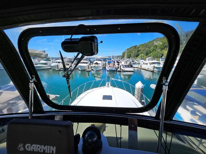 View from Navigator 4300 boat cockpit, overlooking marina with docked boats, clear blue sky.