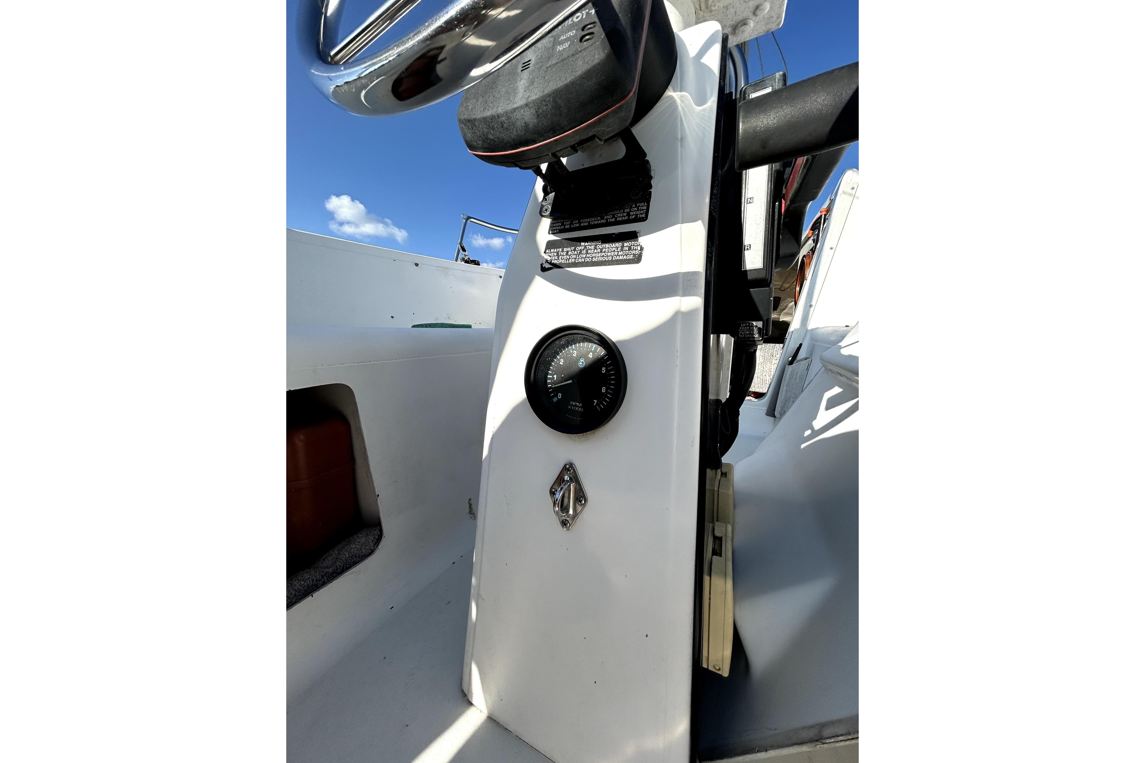 1998 MacGregor 26X Powersailer cockpit with steering wheel and compass under clear blue sky.