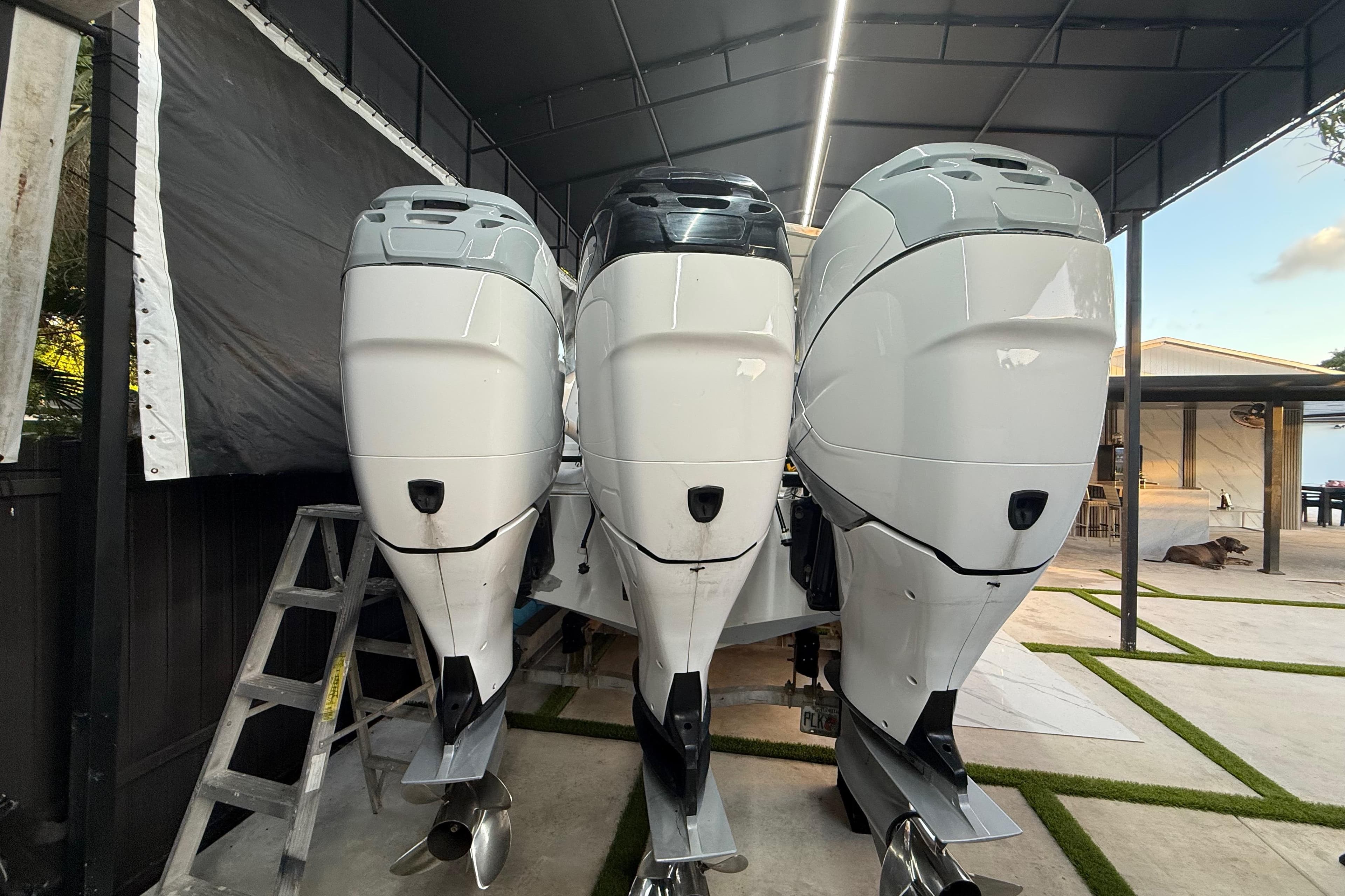 Three powerful outboard motors on a 2005 Formula 330 Sun Sport boat under a canopy.