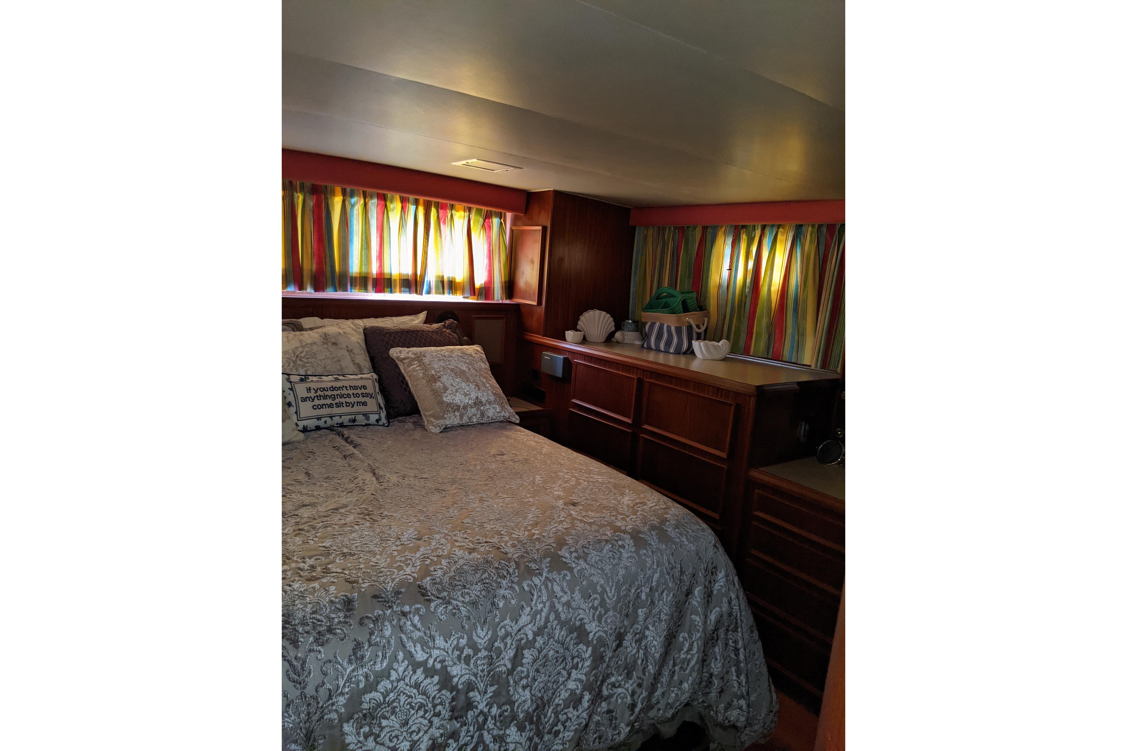 Cozy bedroom in 1984 Hatteras 53 Motor Yacht with colorful curtains and elegant bedding.
