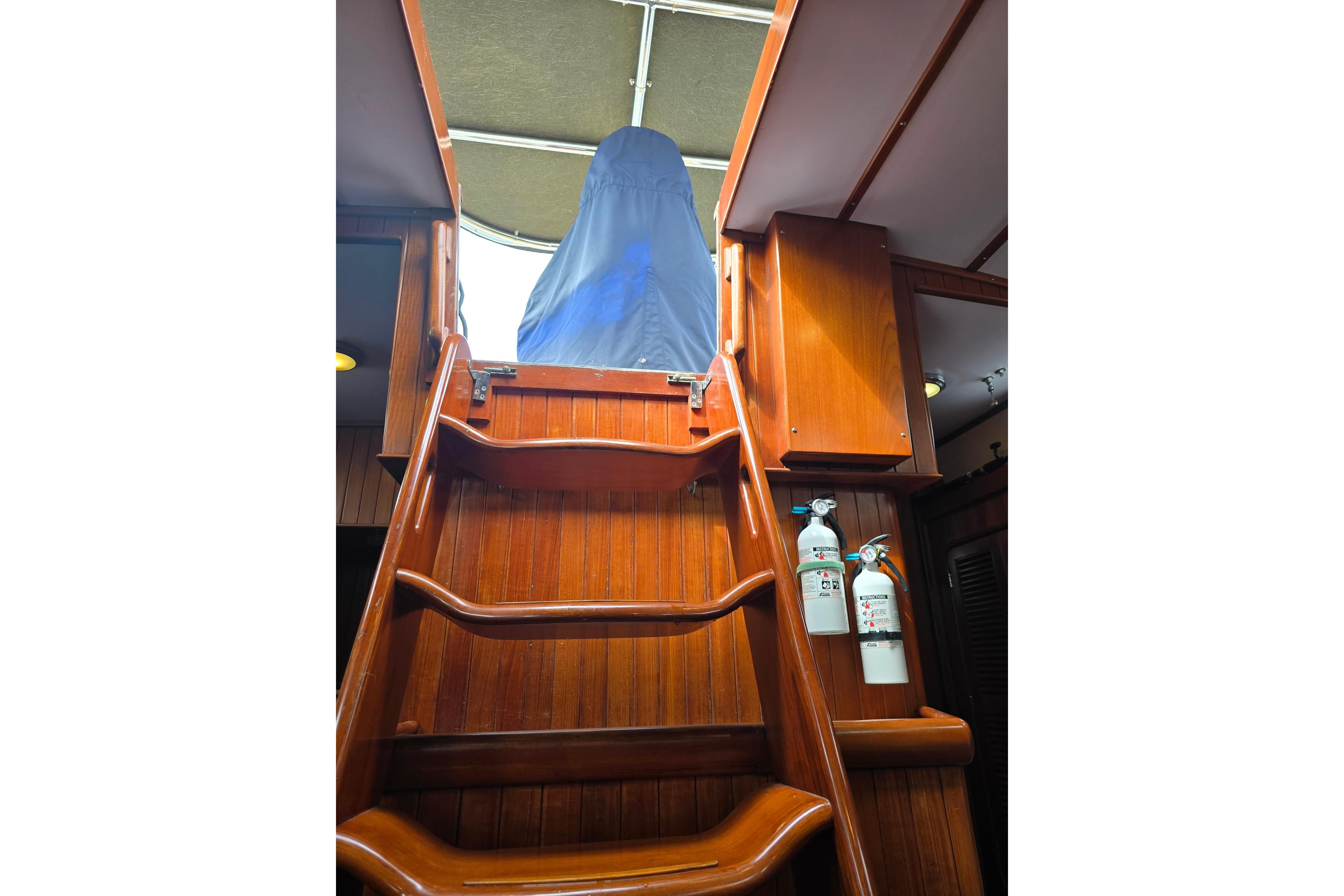 Wooden interior stairs on a 2006 Tayana Vancouver 42 yacht, with fire extinguishers mounted.