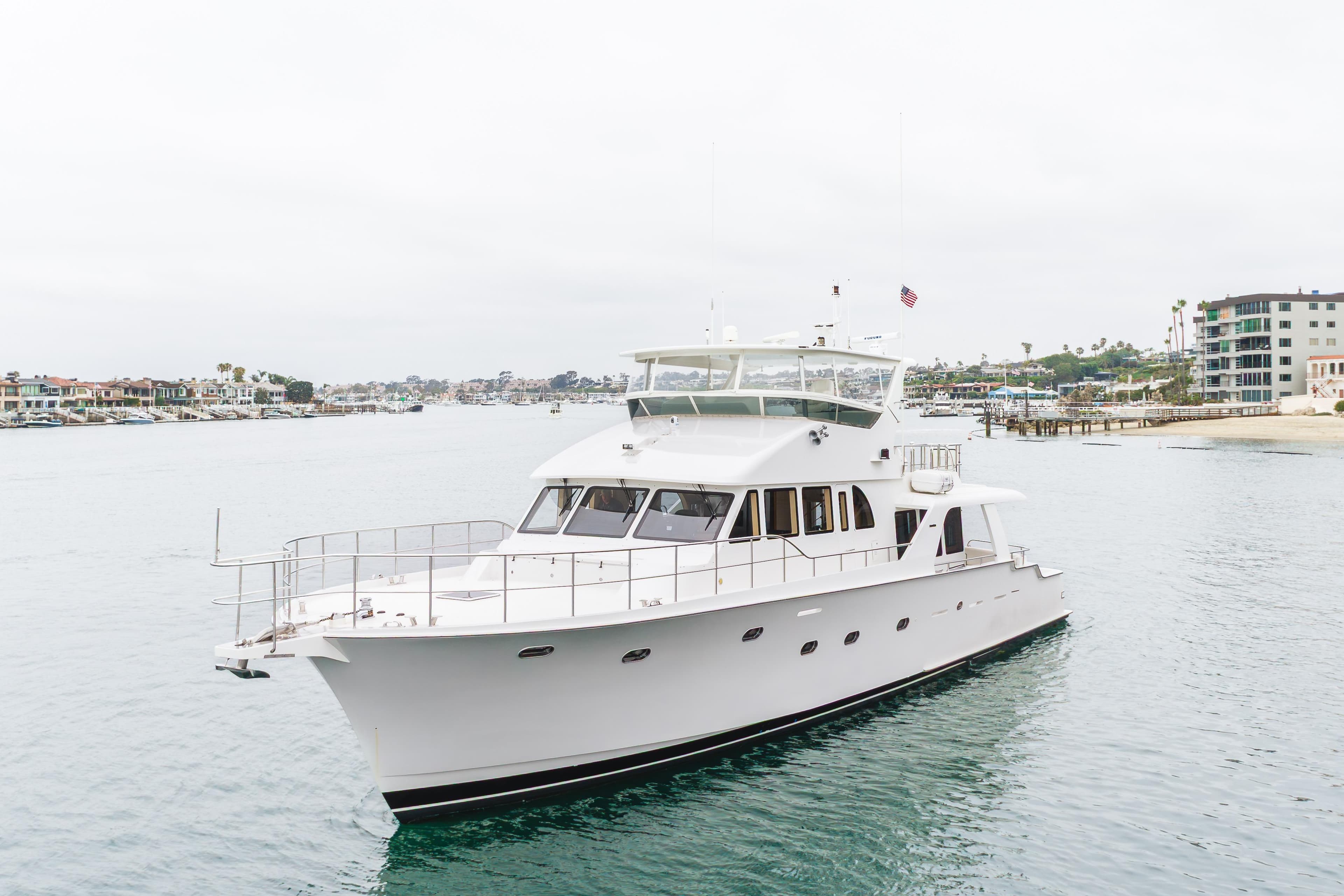 2006 Cheoy Lee 72' Raised Pilot House yacht cruising near coastal homes.