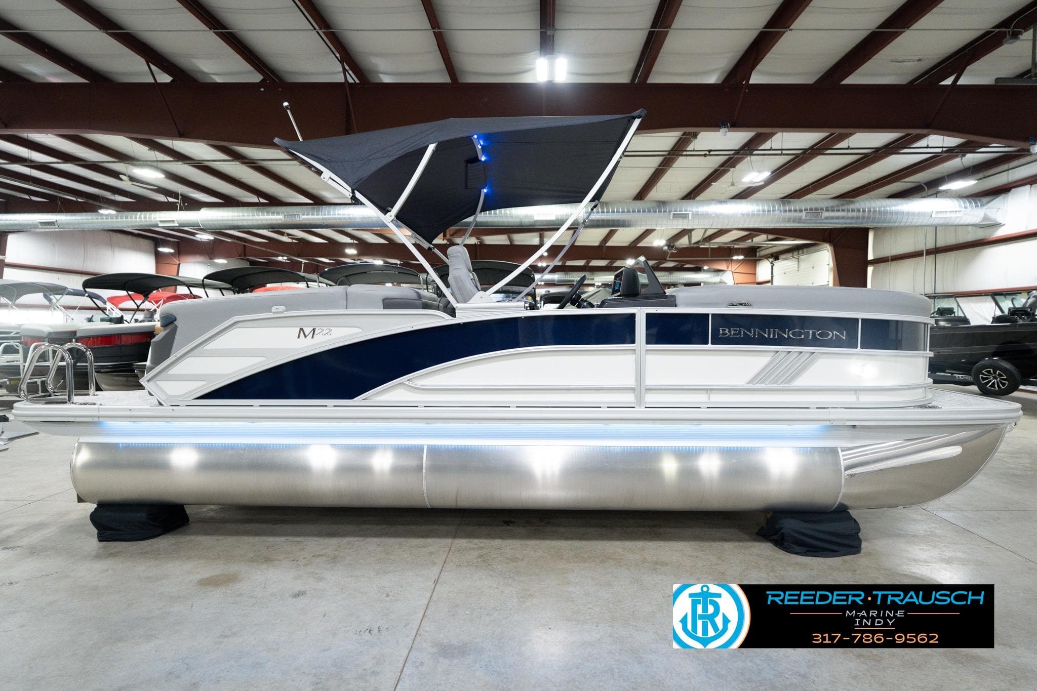 2026 Bennington 22 MFB pontoon boat in showroom with canopy and sleek design.