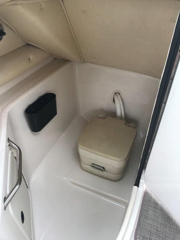 2003 Sea Ray 240 Sundeck interior with portable toilet and storage compartment.