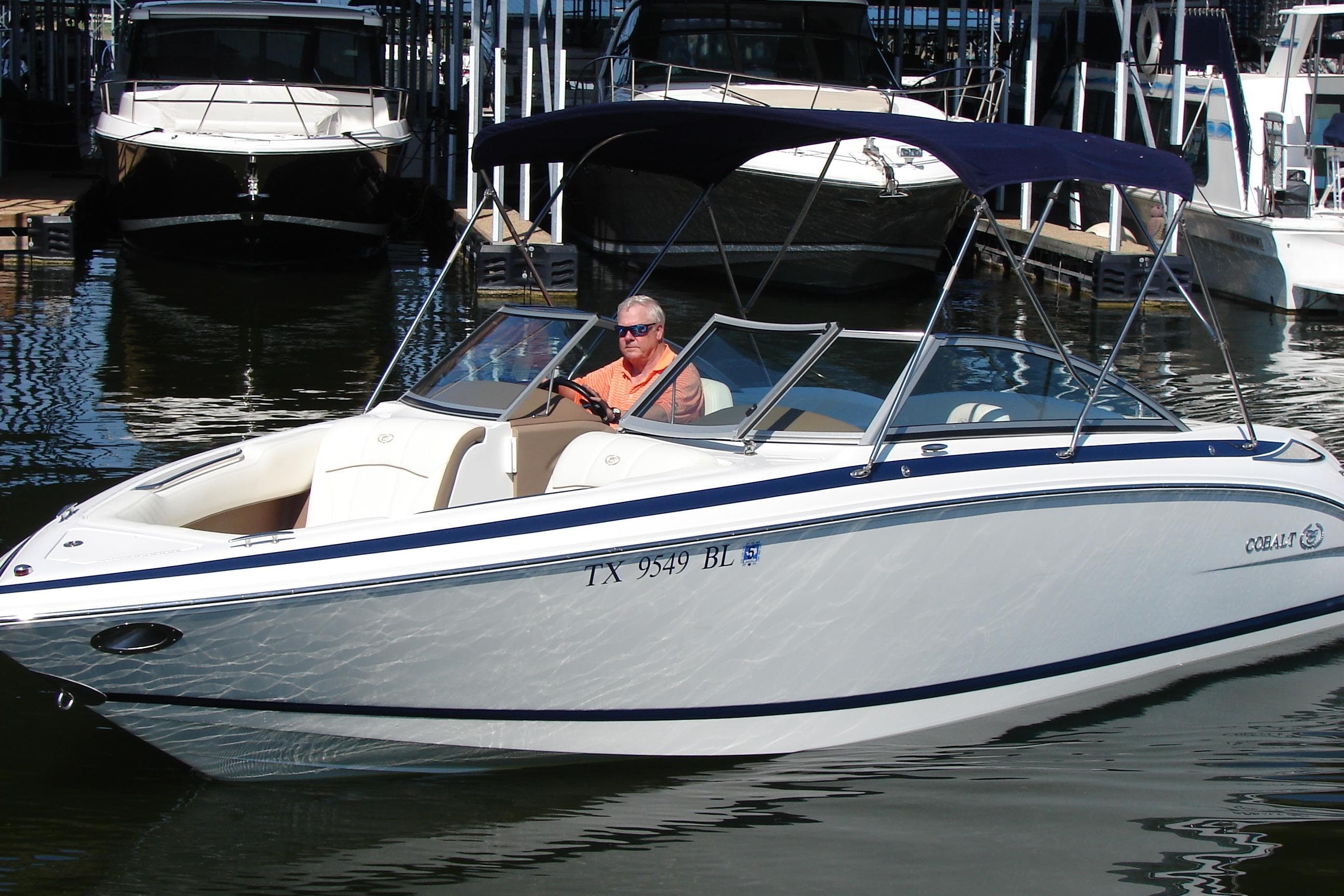 2011 Cobalt 232 boat with canopy, docked in marina, person at helm.