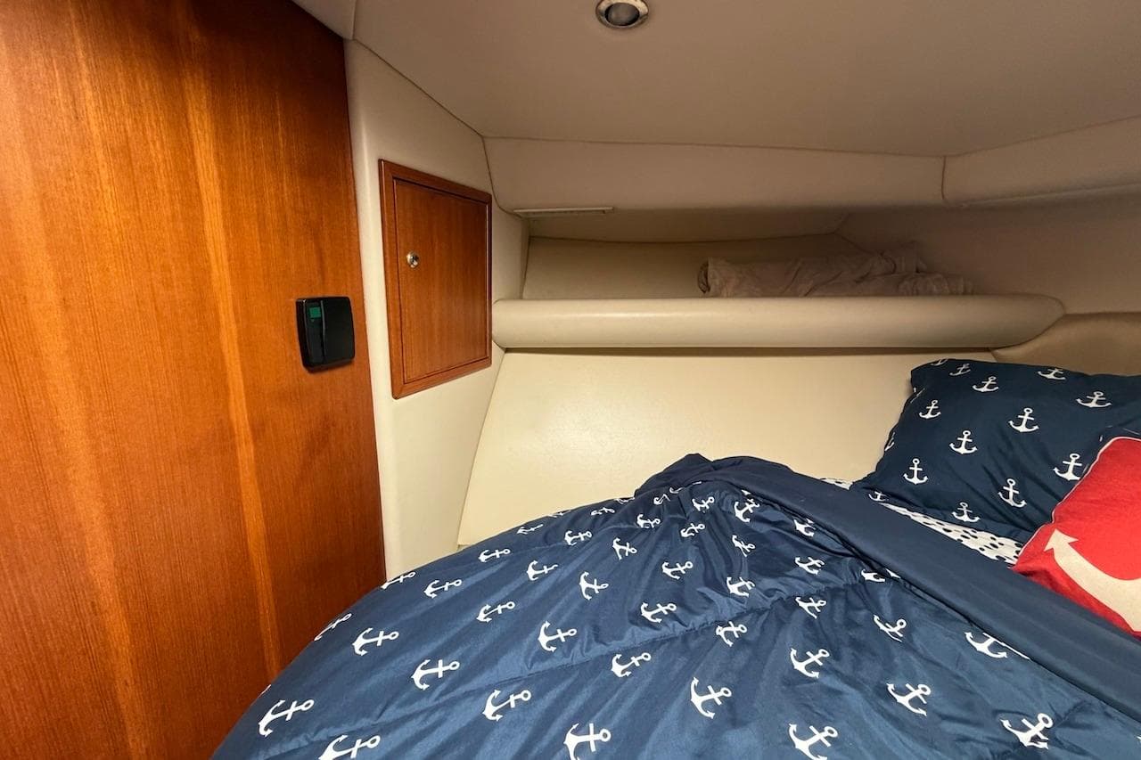 Cozy cabin interior of 2005 Riviera 37 Flybridge with nautical-themed bedding.