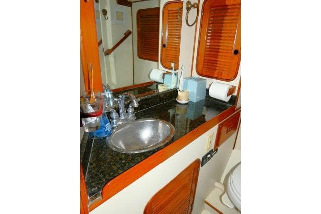 1982 Ta Shing Mason 63 yacht bathroom with sink, mirror, and wooden accents.
