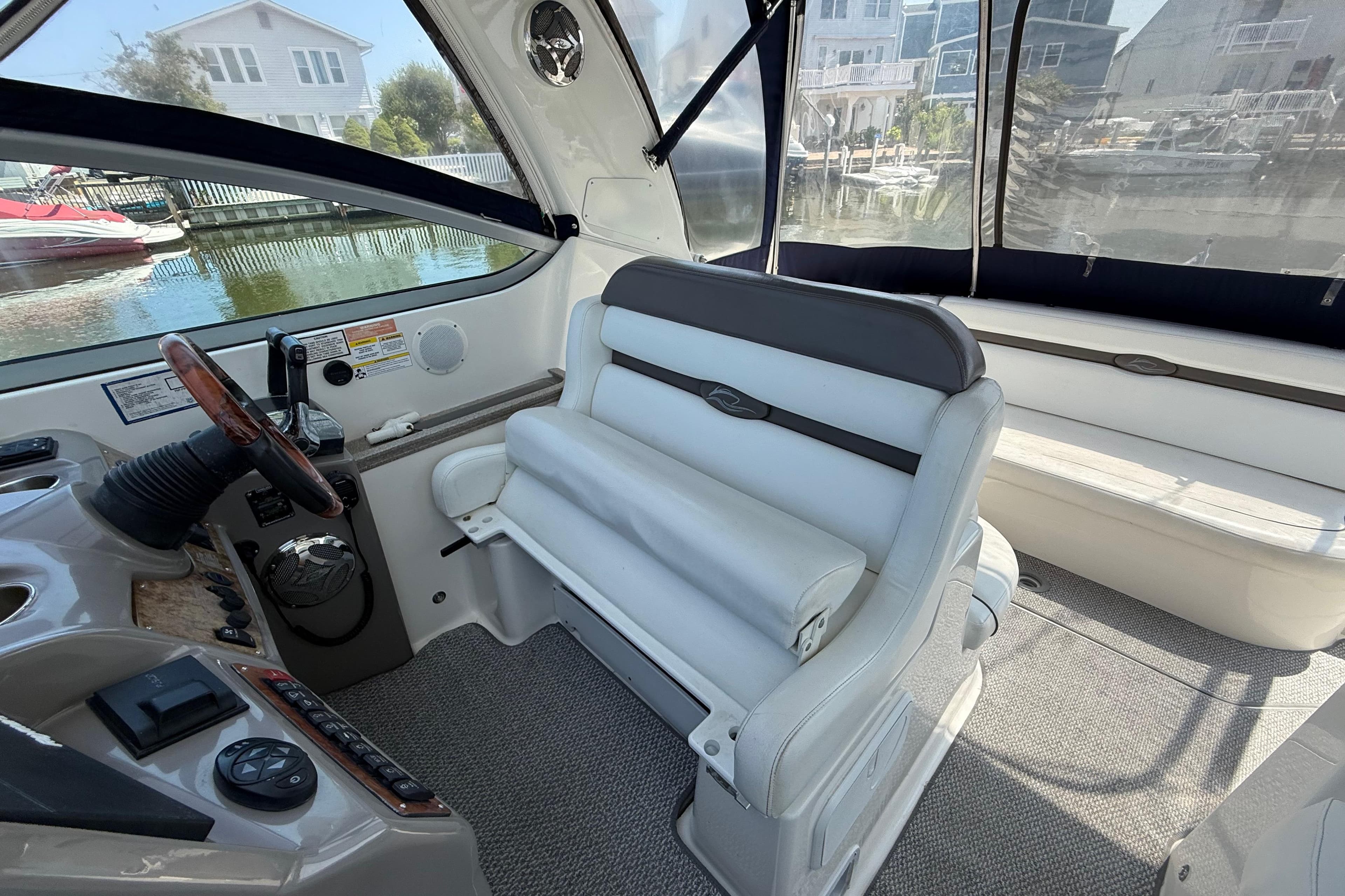 2009 Rinker 340 Express Cruiser interior with helm and seating, docked near waterfront homes.