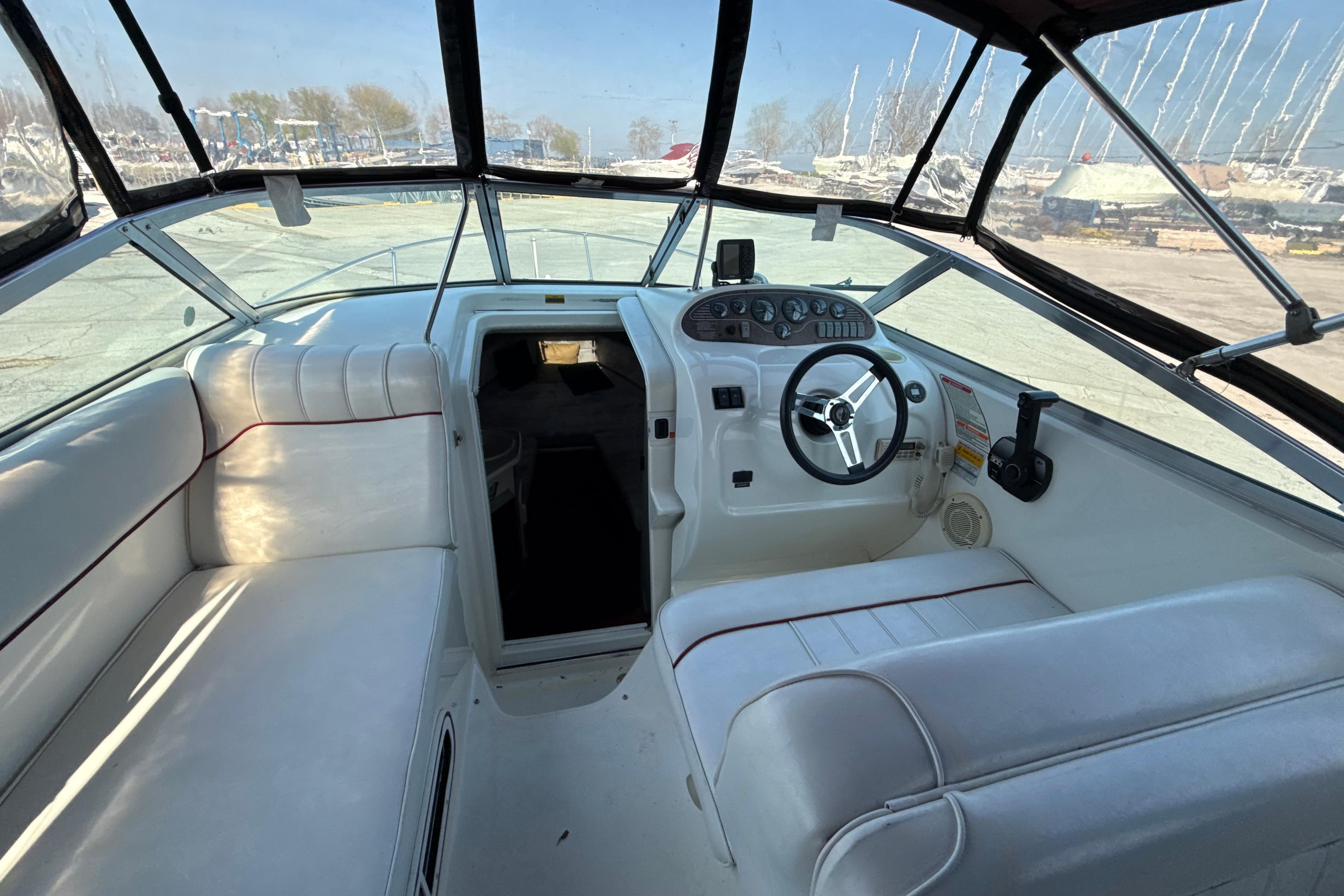 1996 Sea Ray 240 Sundancer boat interior with white seating and steering console.
