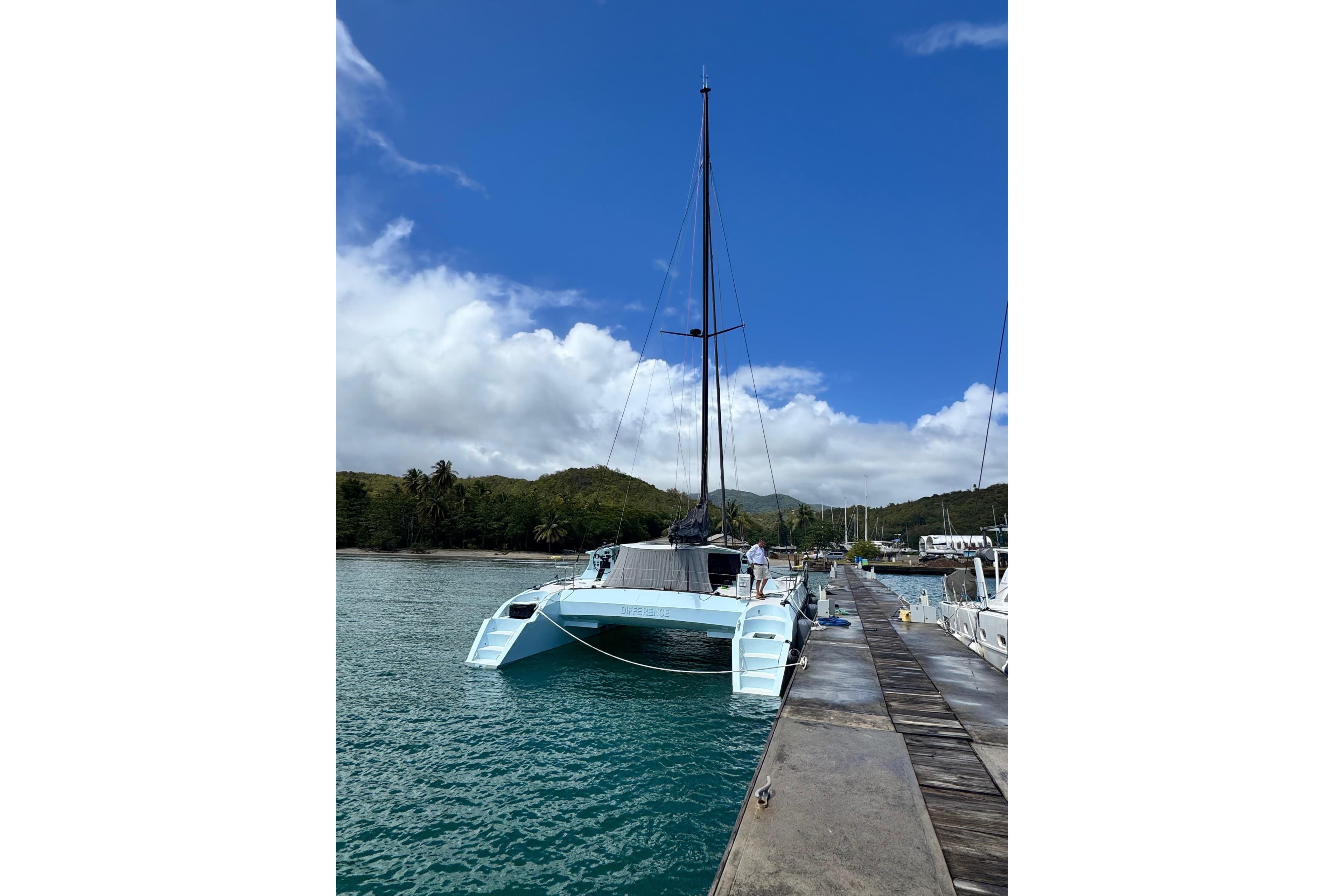 Sleek 2011 Alibi 54 catamaran docked in a tropical marina under a clear blue sky.