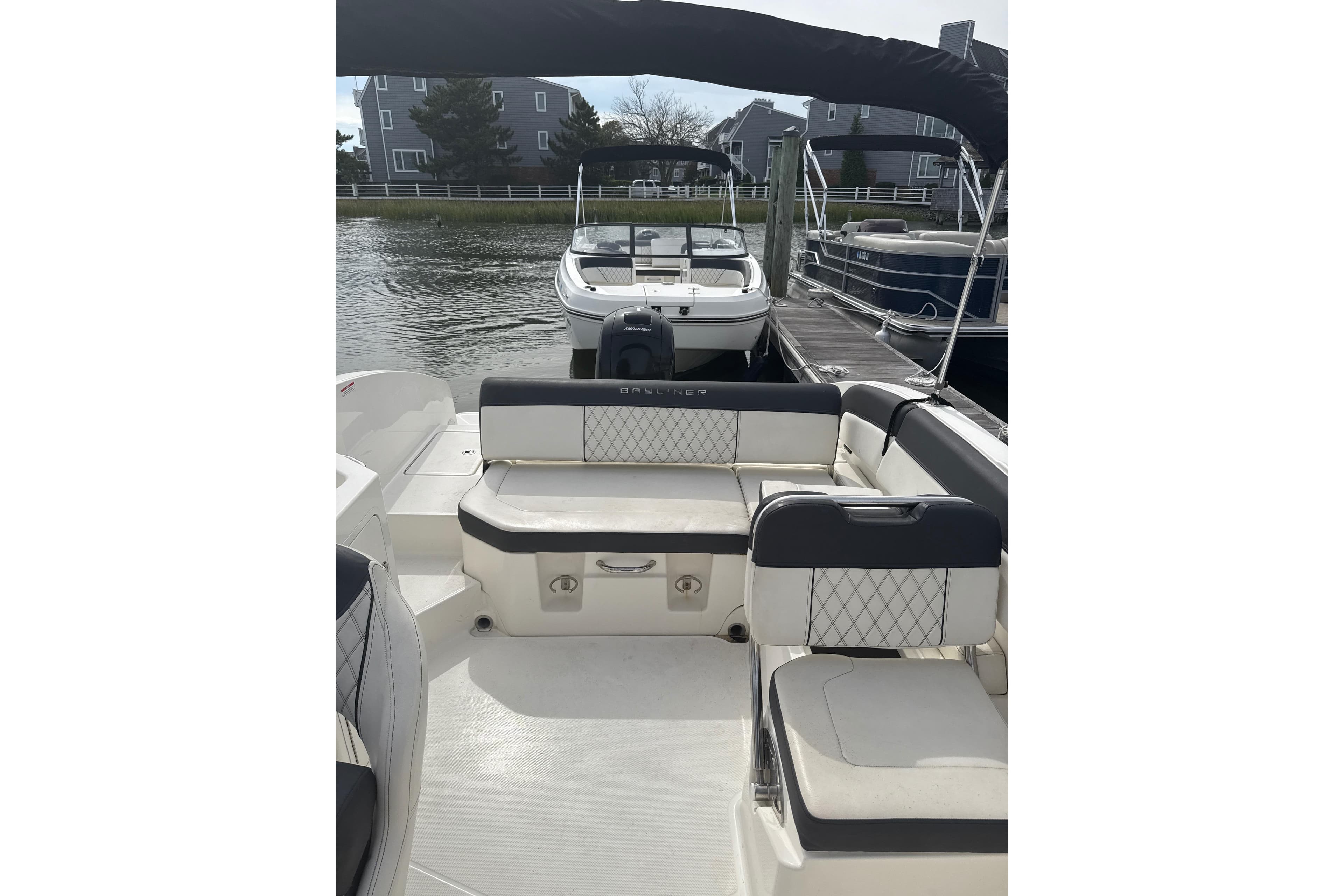 2023 Bayliner DX 2200 boat interior with cushioned seating at a marina.