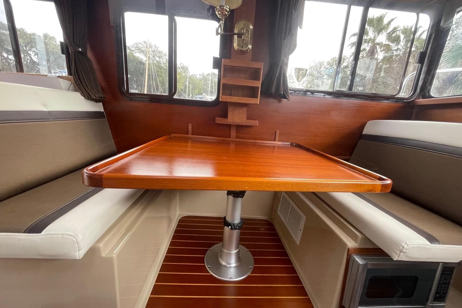 Interior of 2012 Ranger Tugs R-27 with wooden table and cushioned seating.