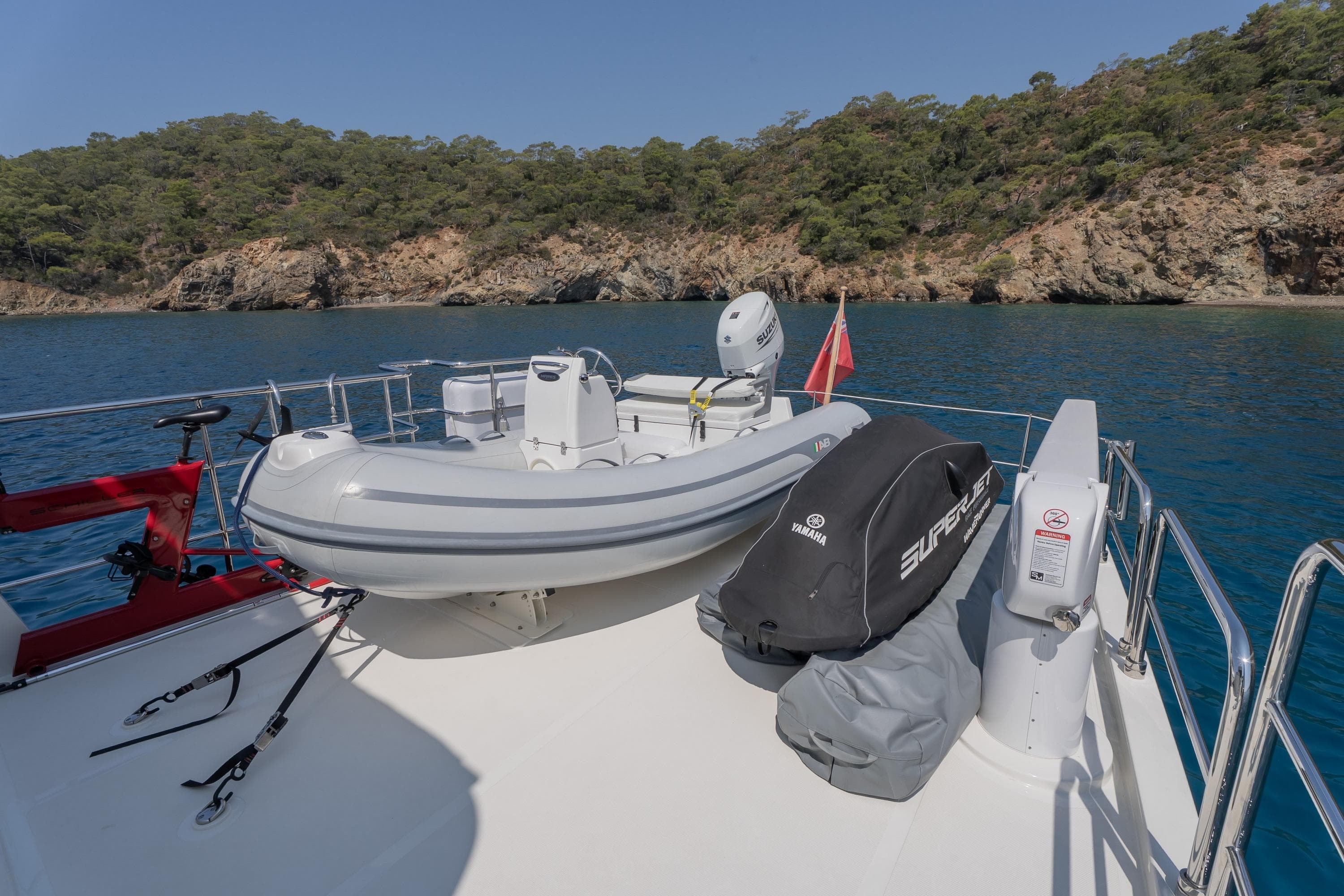 2024 Nordhavn 51 yacht deck with inflatable boat and Yamaha SuperJet, scenic coastal backdrop.