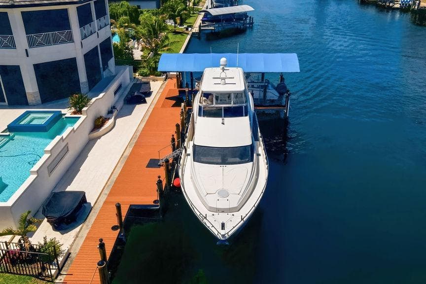 Luxury 2006 Marquis 59 yacht docked beside waterfront property with pool.