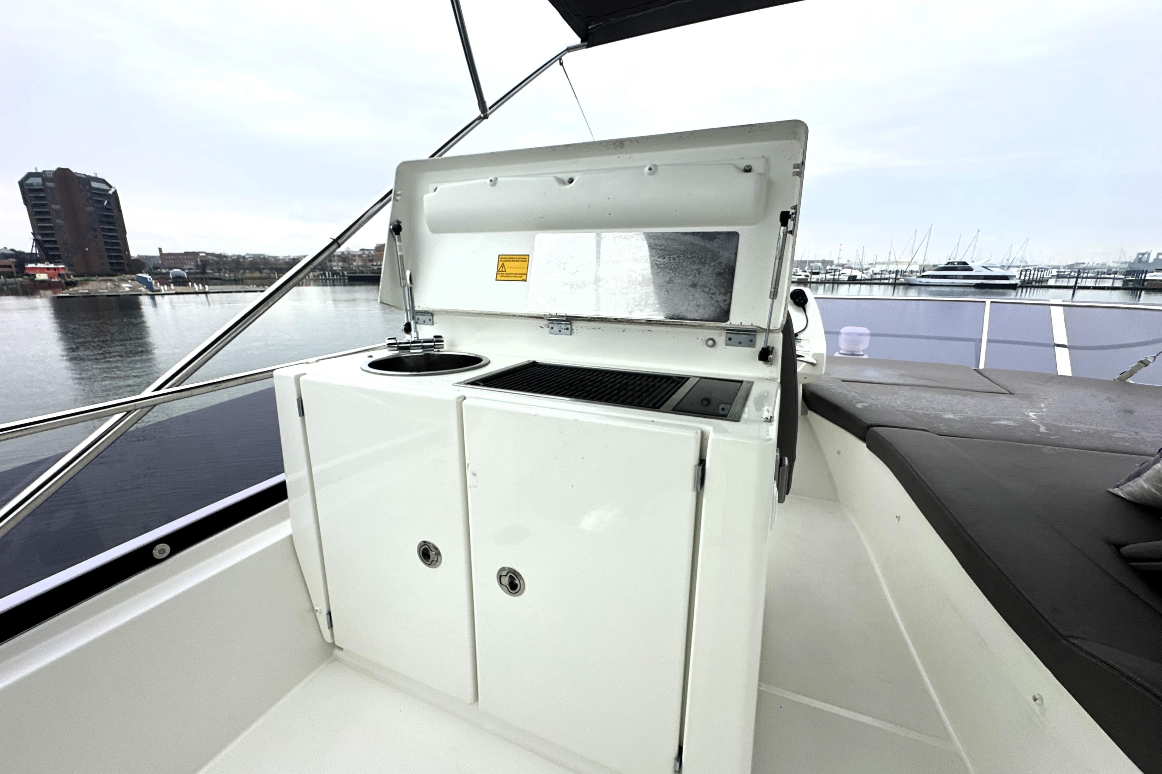 Outdoor kitchenette on 2017 Prestige 500 yacht, featuring grill and sink, dockside view.