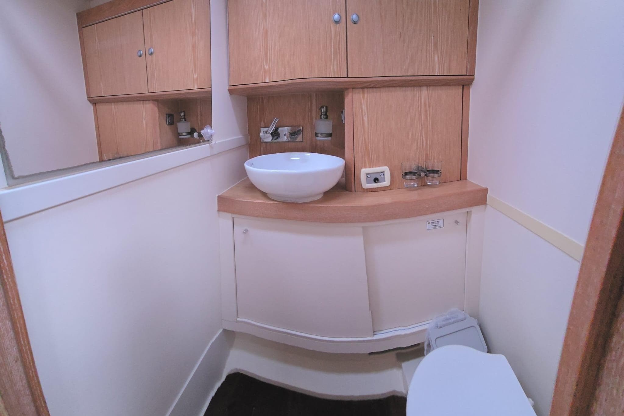 Bathroom interior of 2015 Hanse 575 yacht with wooden cabinets and modern sink.