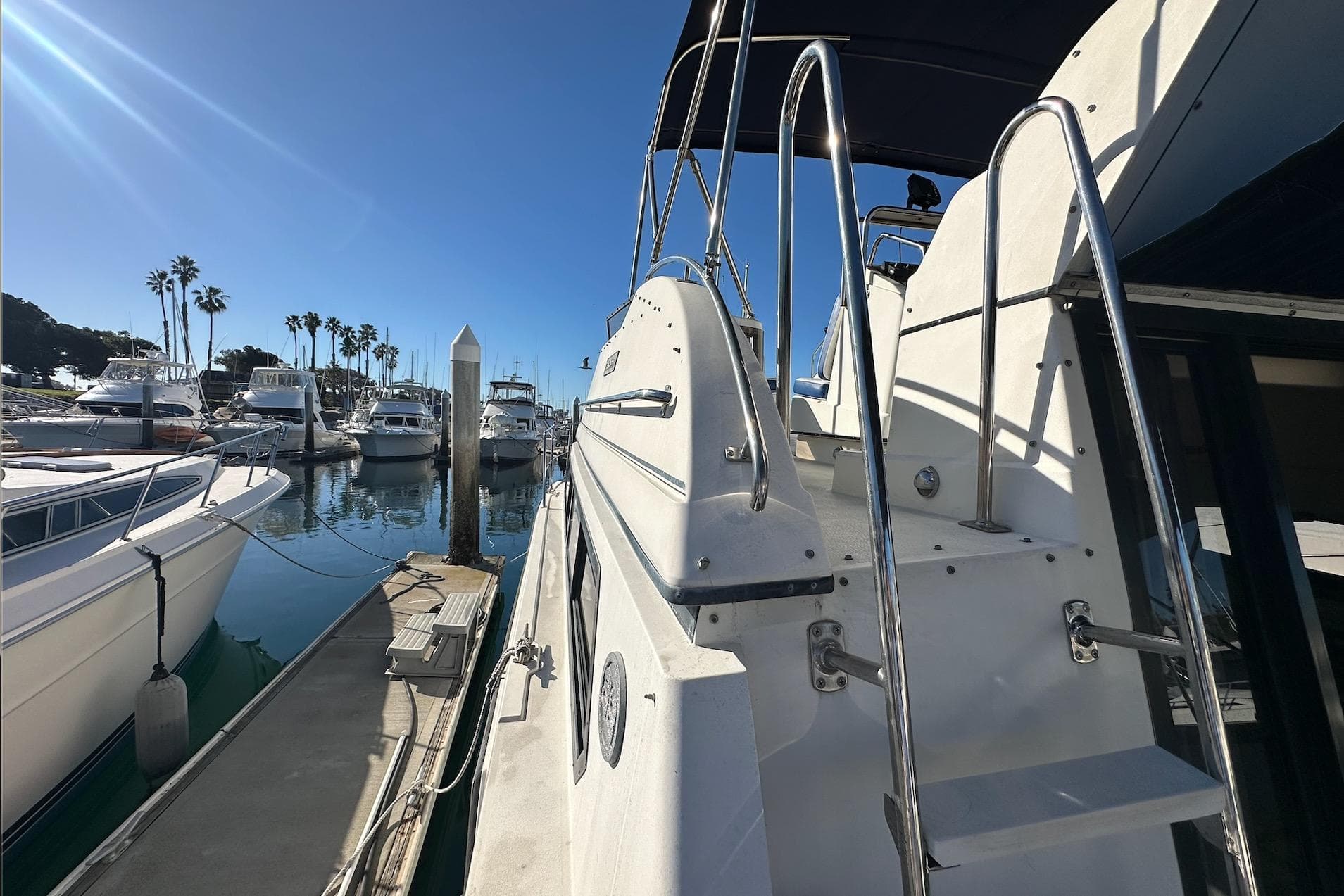 1988 Carver 38 Santego yacht docked at a sunny marina with palm trees.
