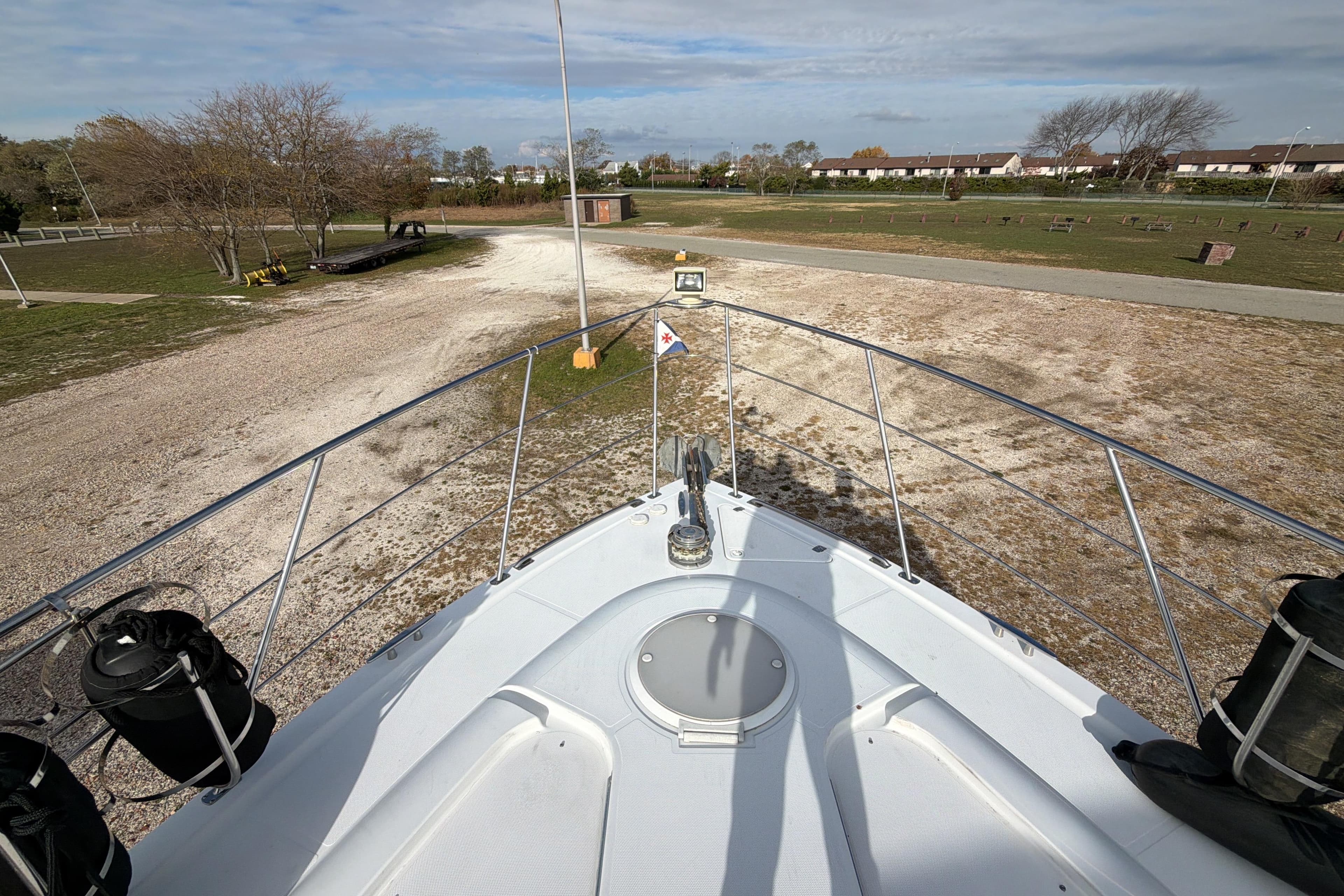 Bow view of 2003 Carver 564 Cockpit Motor Yacht on land, surrounded by trees.