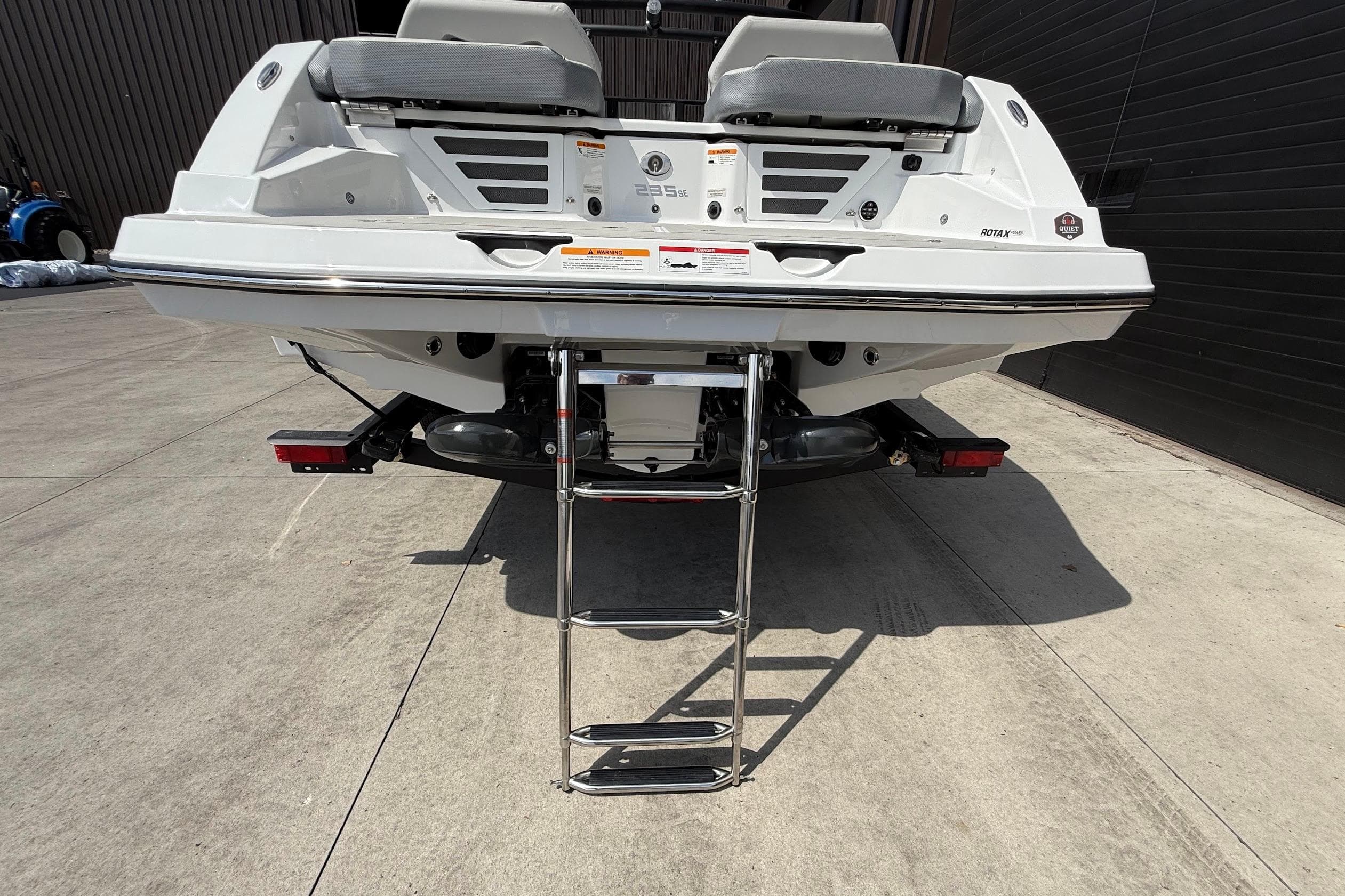 2026 Scarab 235 SE boat rear view with ladder on concrete surface.