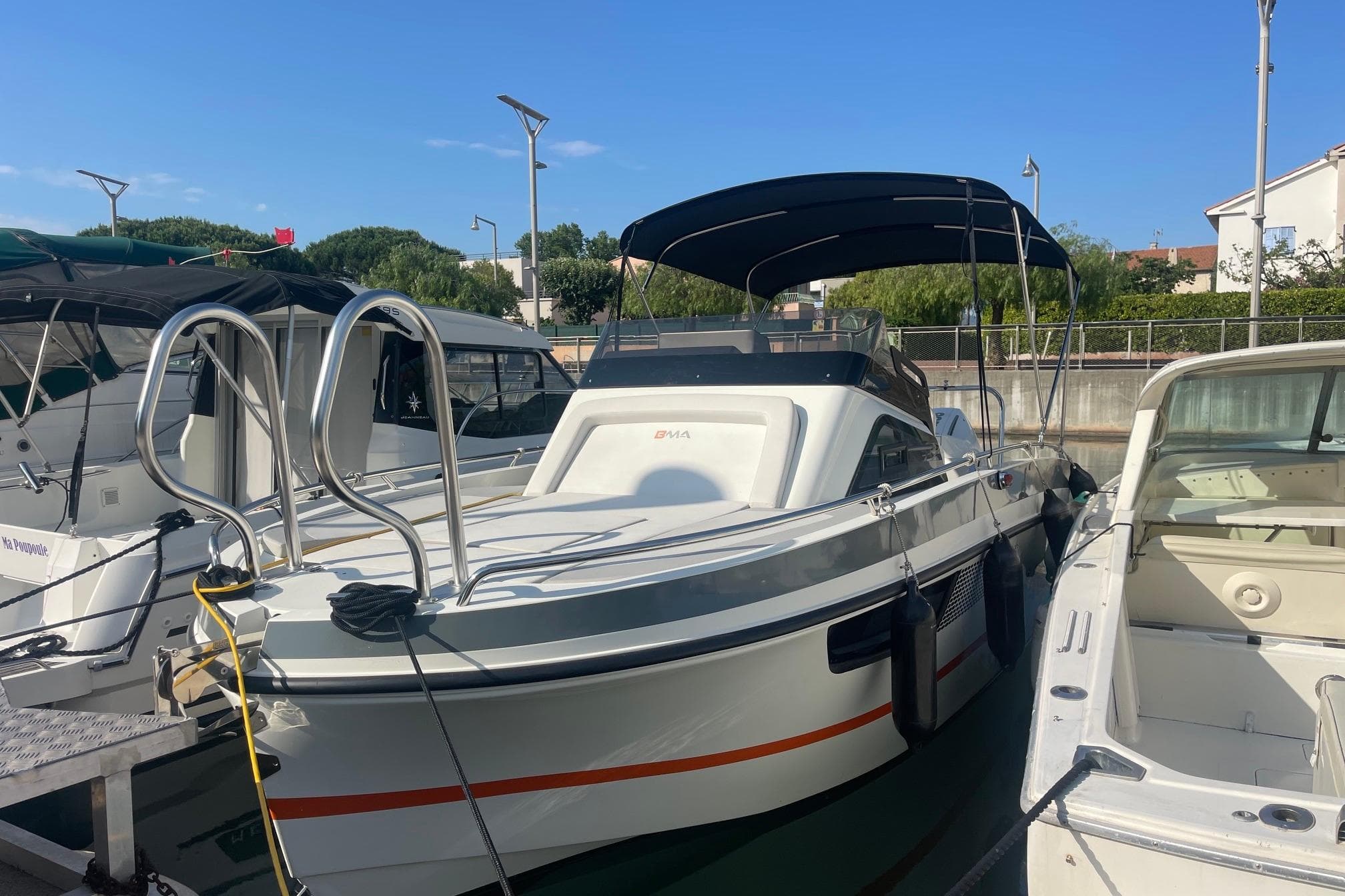 BMA X233 2022 boat docked in marina, featuring sleek design and canopy.