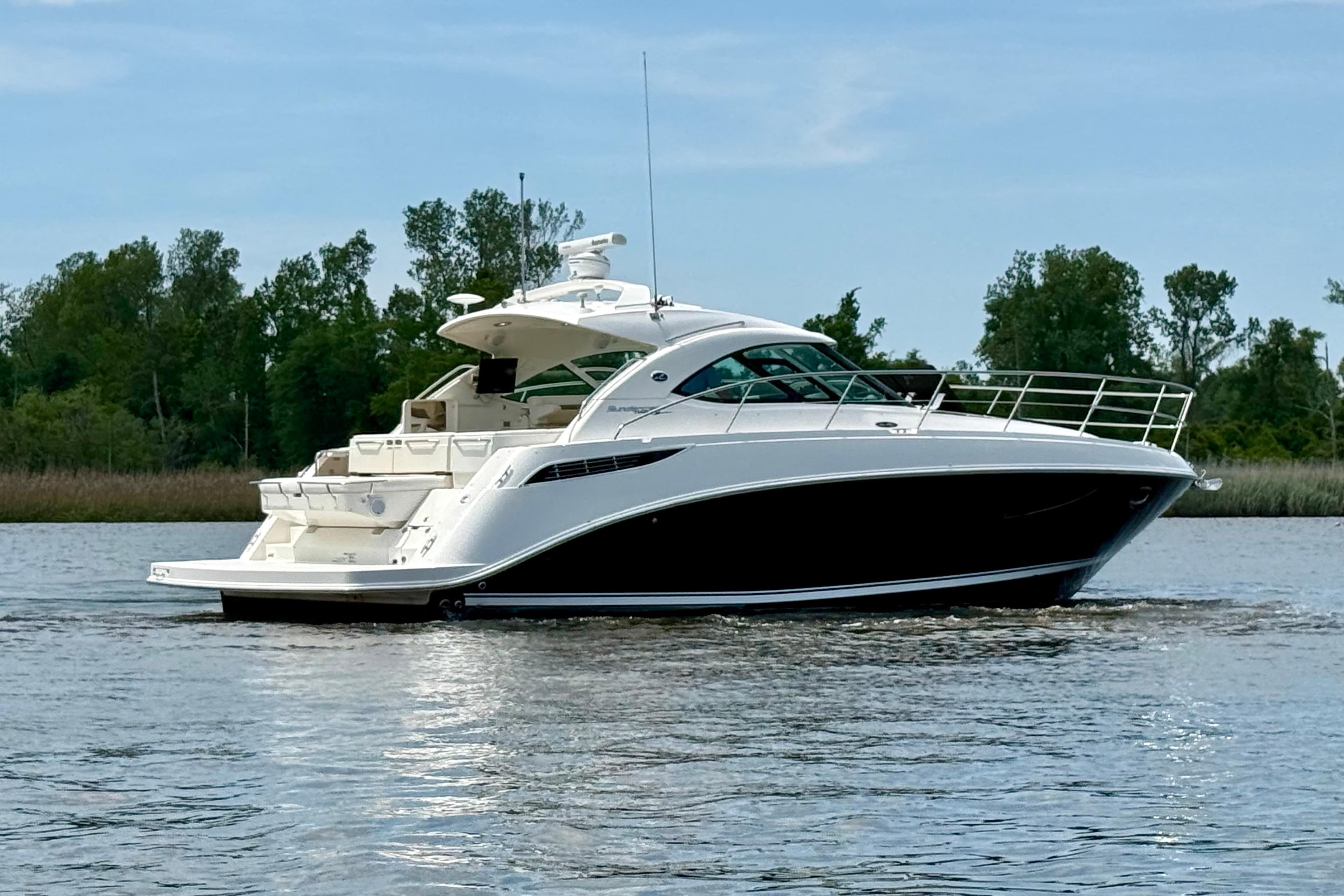 2012 Sea Ray 410 Sundancer yacht cruising on a serene lake with lush greenery.