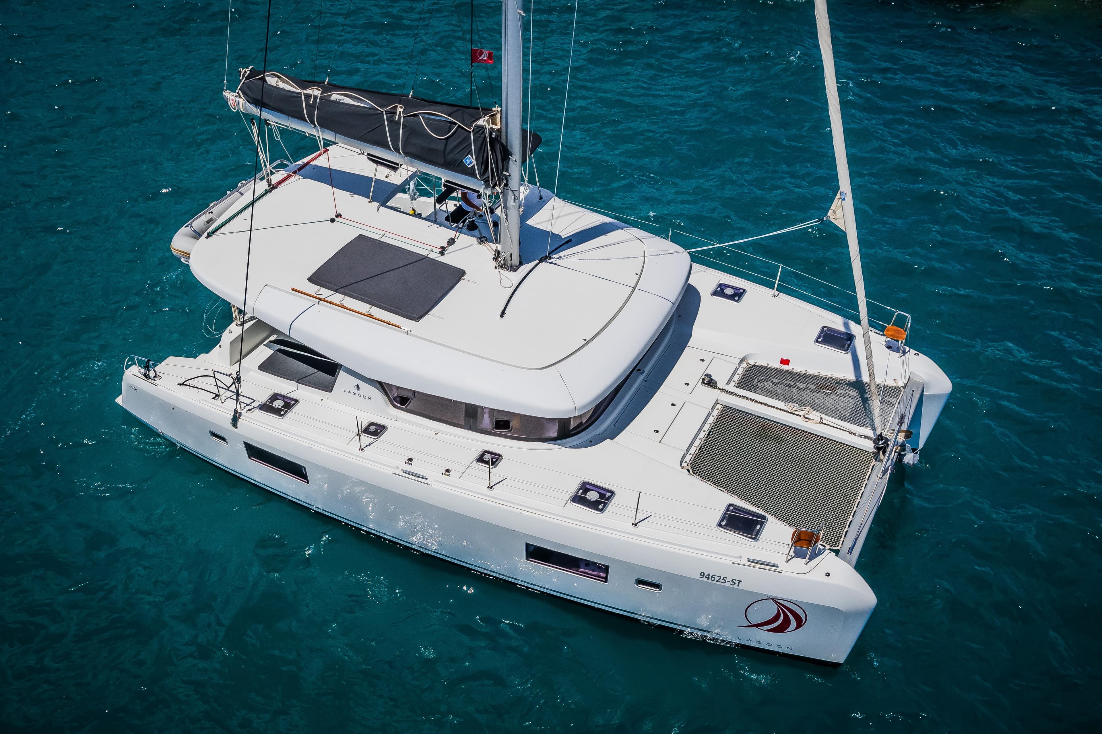 2018 Lagoon 42 catamaran sailing on clear blue water.