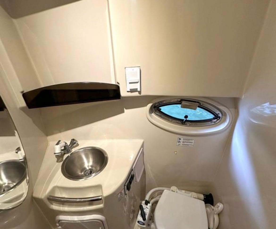 2008 Four Winns V258 boat bathroom with sink, toilet, and porthole window.