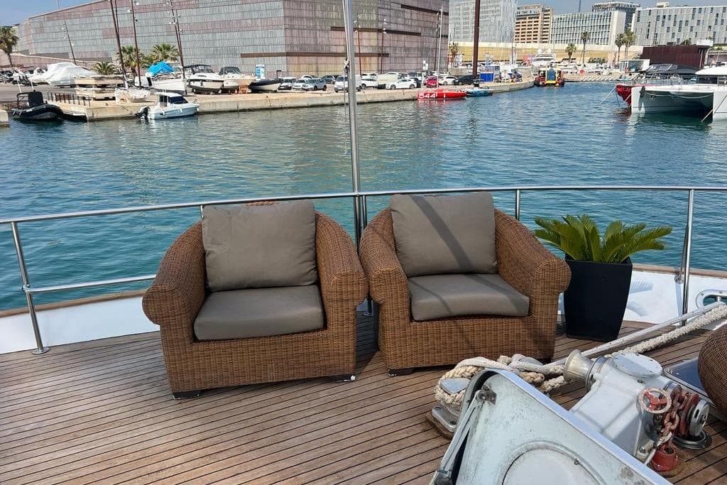 Deck of 1985 Astondoa 24 yacht with wicker chairs and marina view.