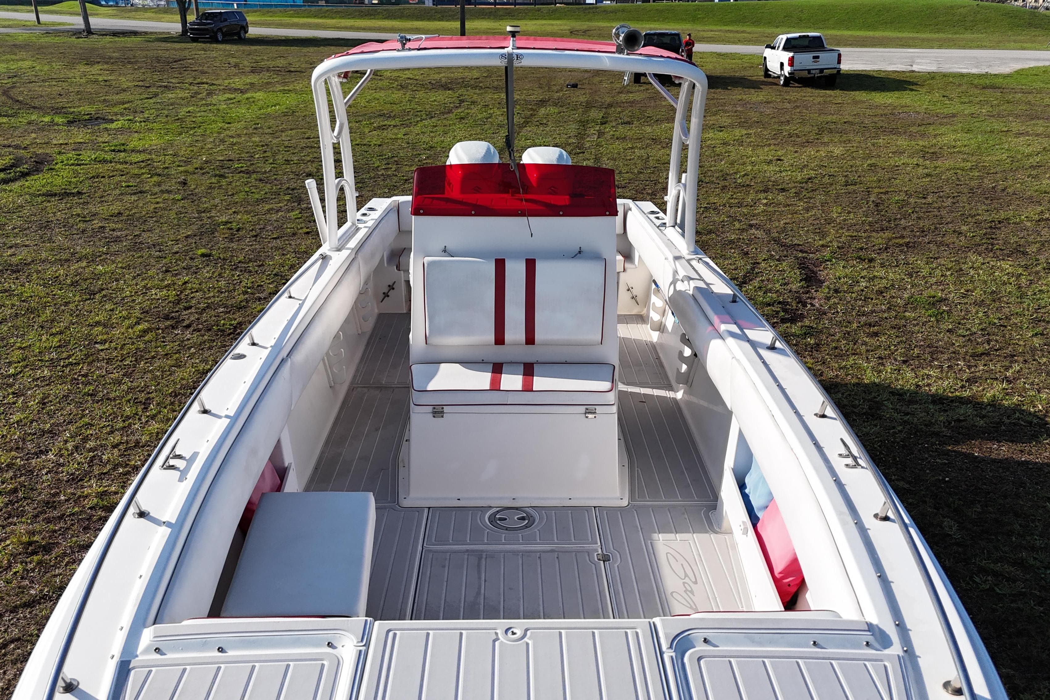1992 Baja 280 Sportfish boat with red and white seating, parked on grass.