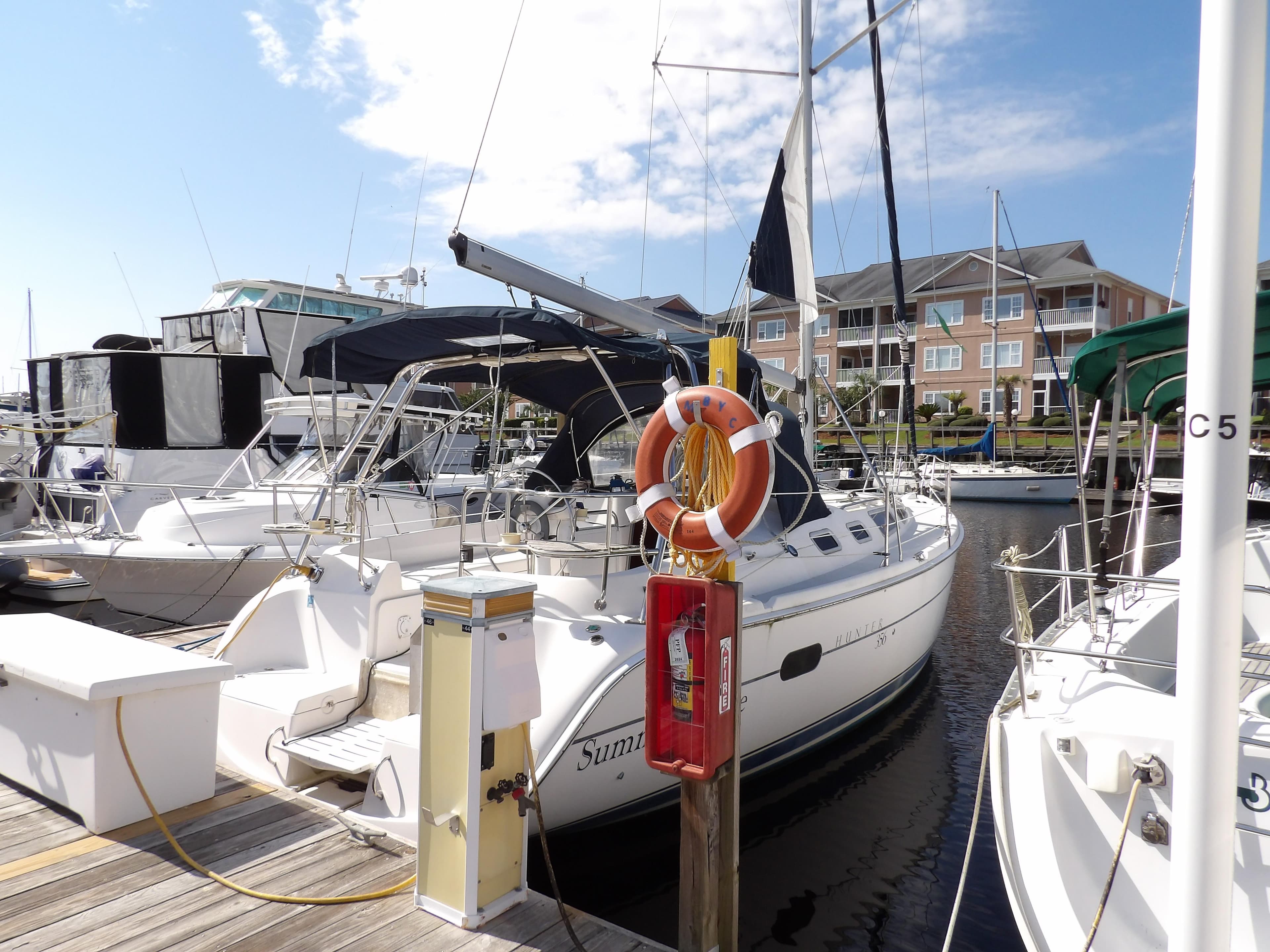2002 Hunter 356 sailboat docked at marina with lifebuoy and clear sky.