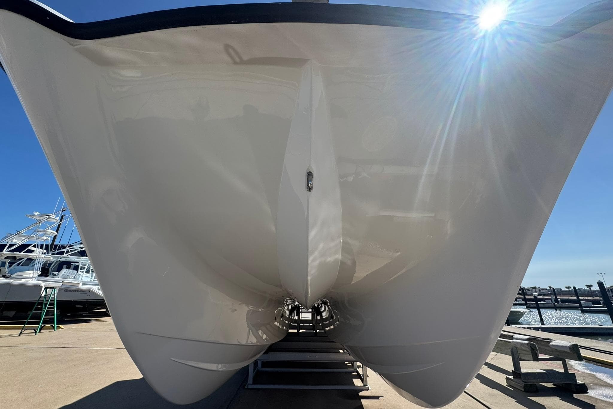 2023 Twin Vee 400 GFX CC catamaran hull under bright sunlight at a marina.
