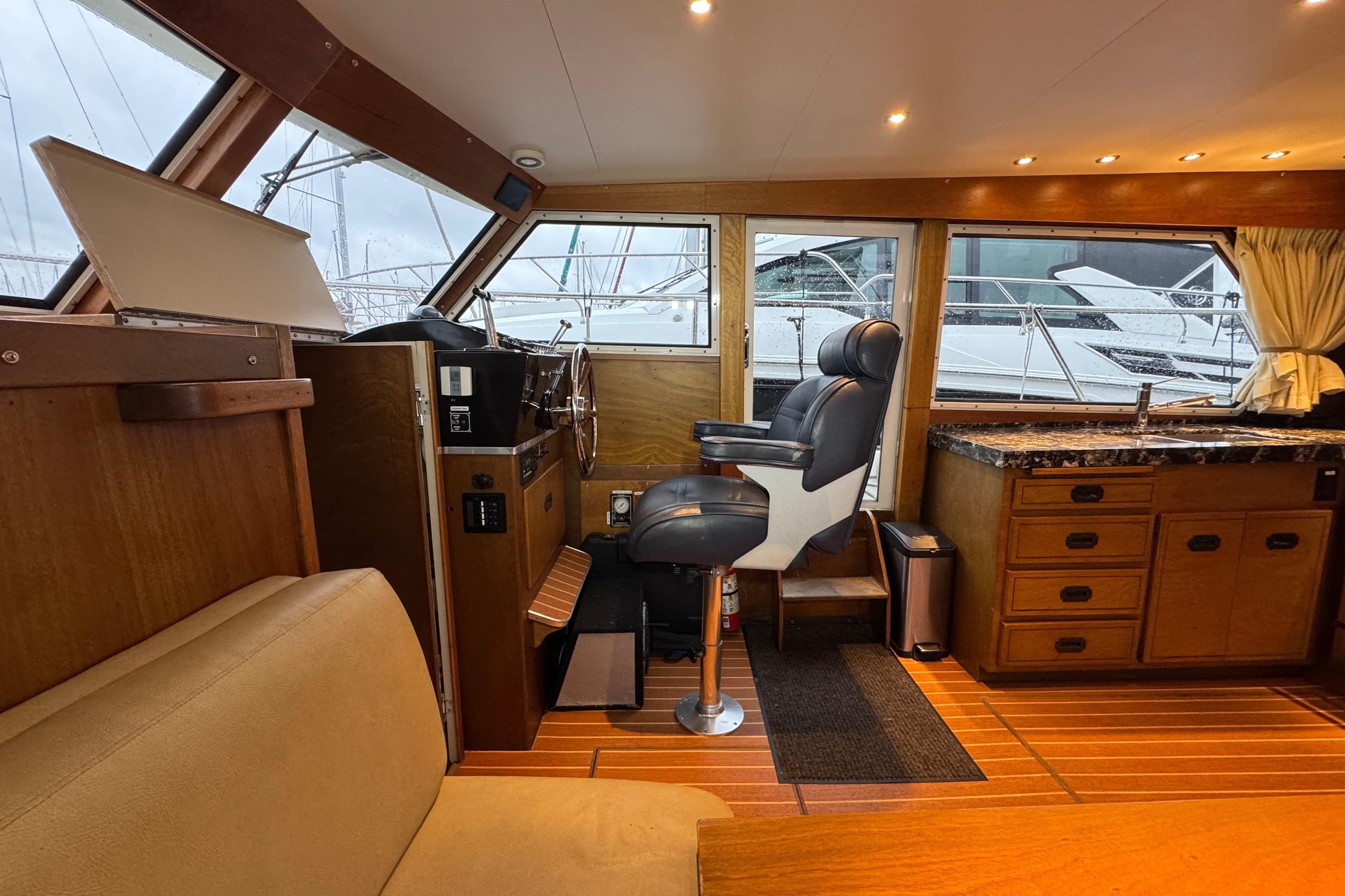 1974 Tollycraft 40 Tri-Cabin MY interior with helm, seating, and kitchenette.